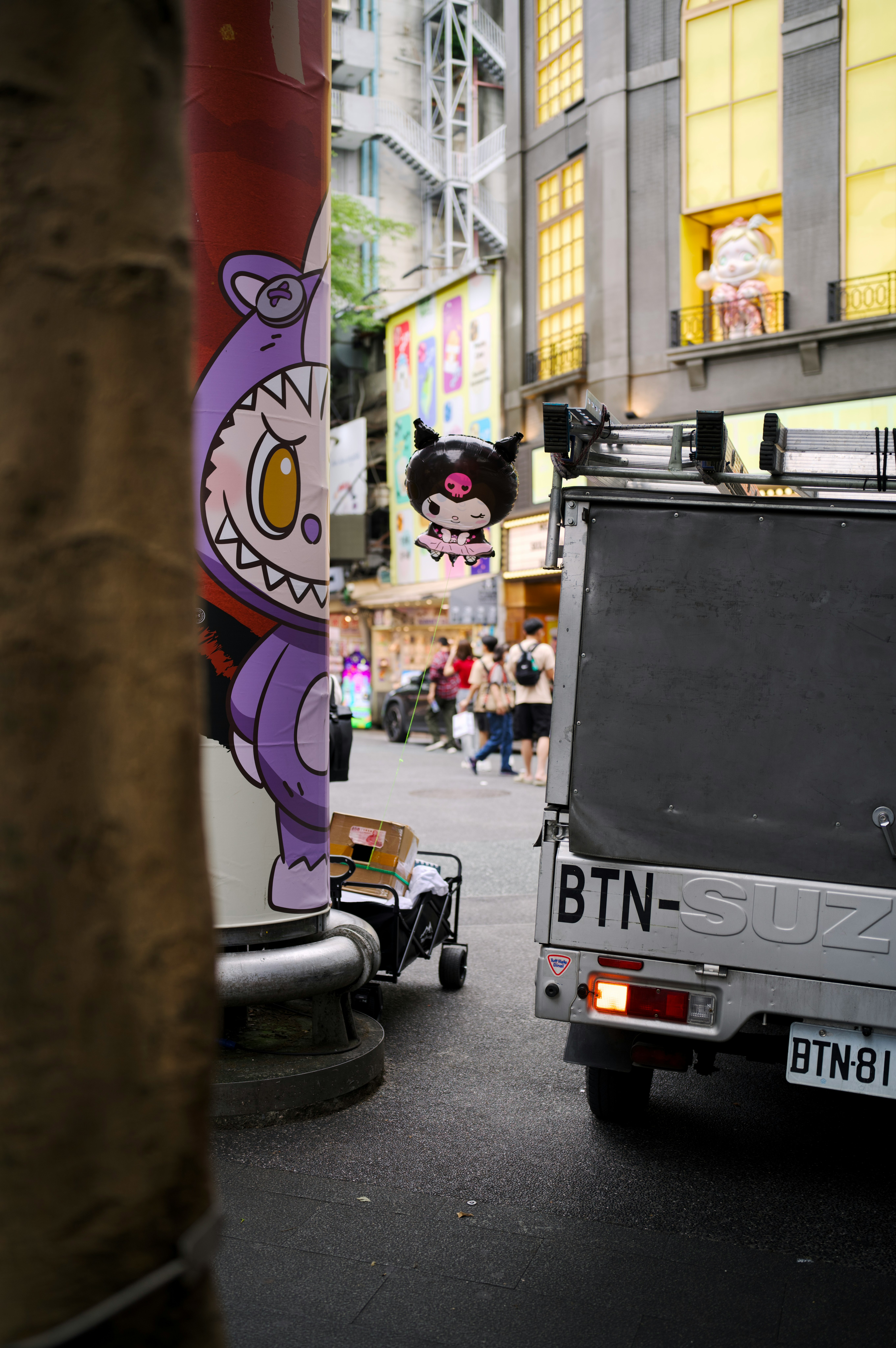 路地の壁に描かれたキャラクターと小さなトラックのある街並み