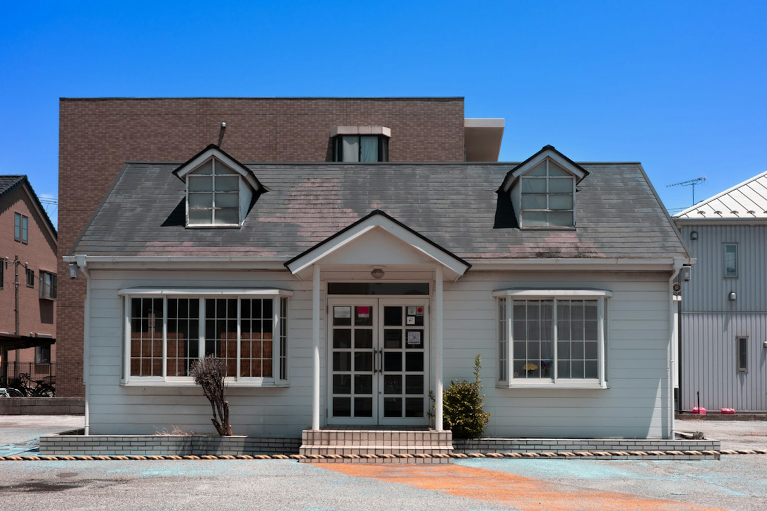 Charming house exterior under a blue sky with distinctive roof and large windows