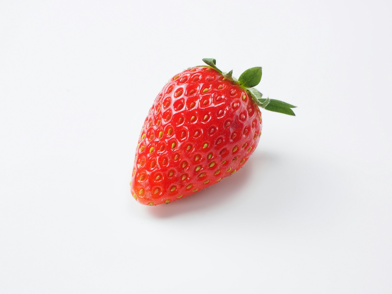 Una fragola rossa vivace posata su uno sfondo bianco