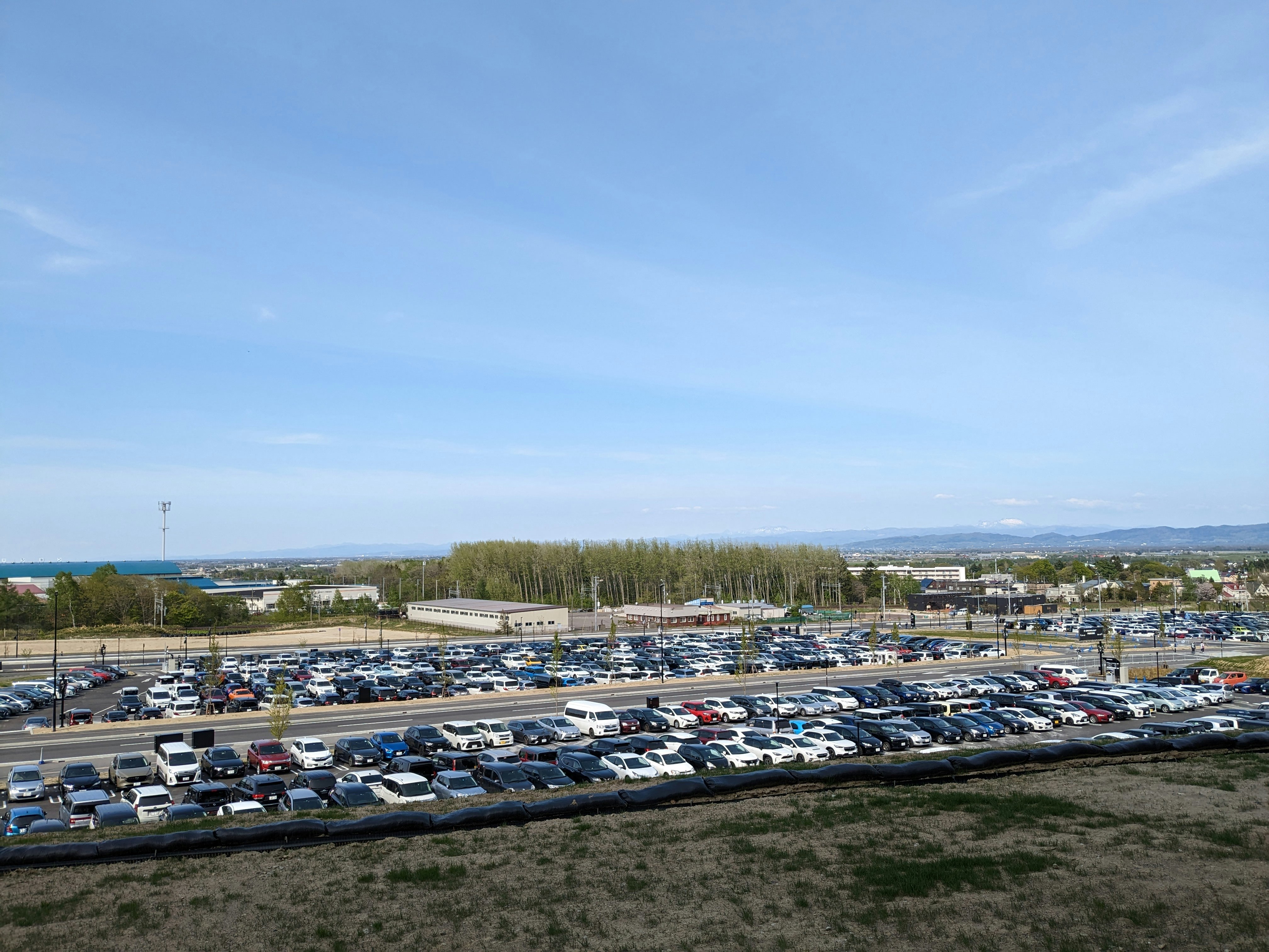 広い駐車場に並ぶ車と青空の風景