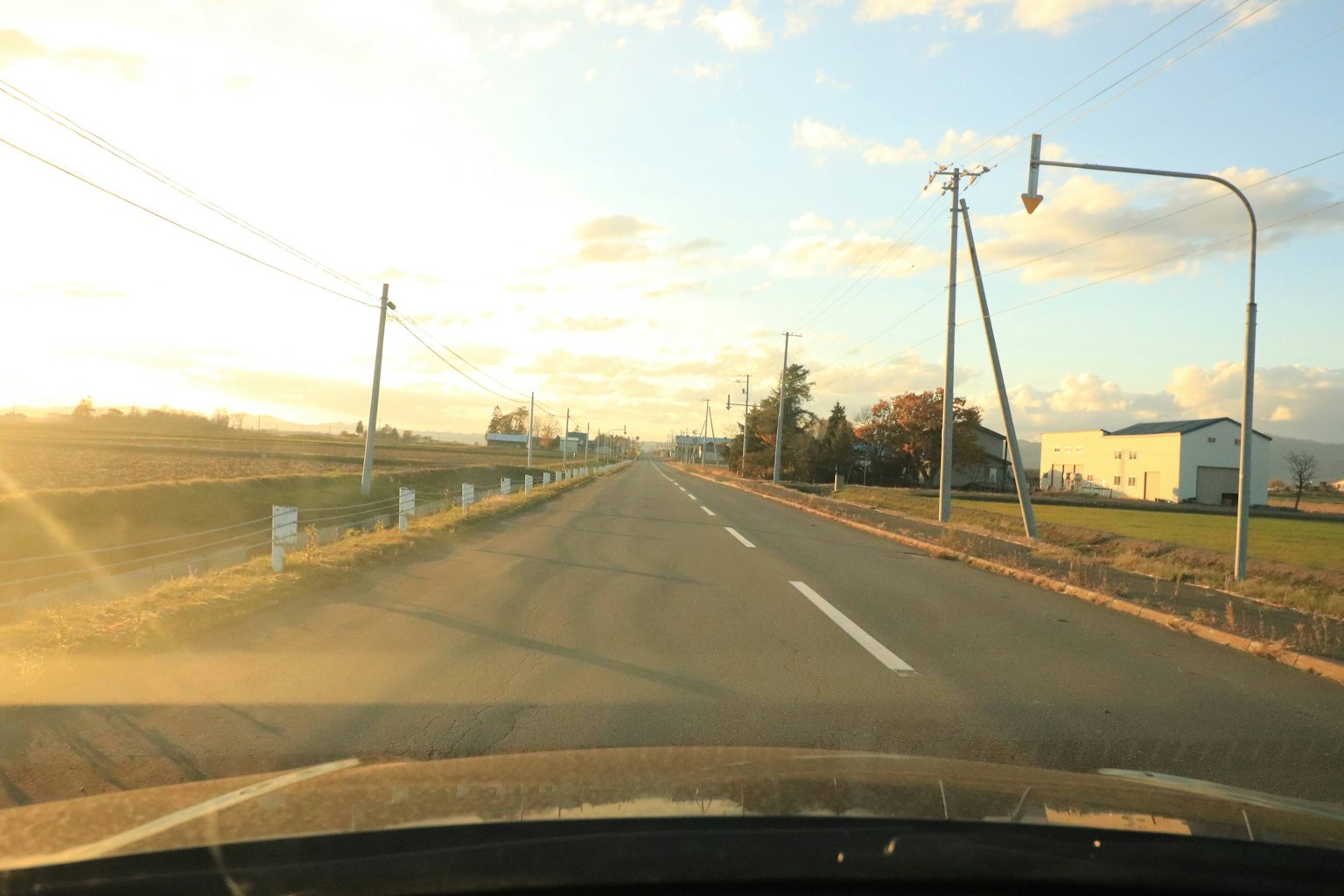 Landstraße bei Sonnenuntergang durch die Windschutzscheibe des Autos gesehen
