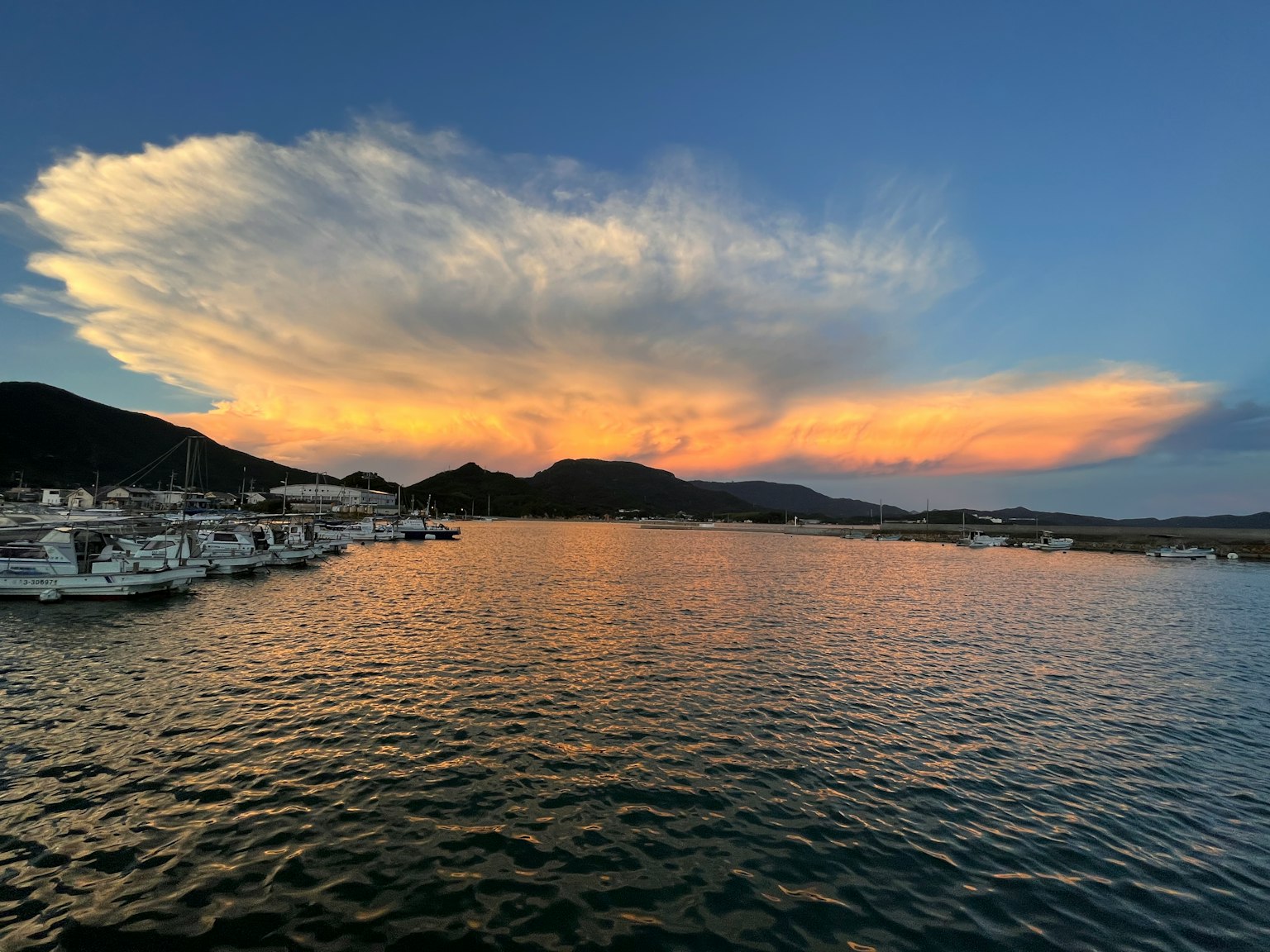 平静海面上的日落与港口里的船只