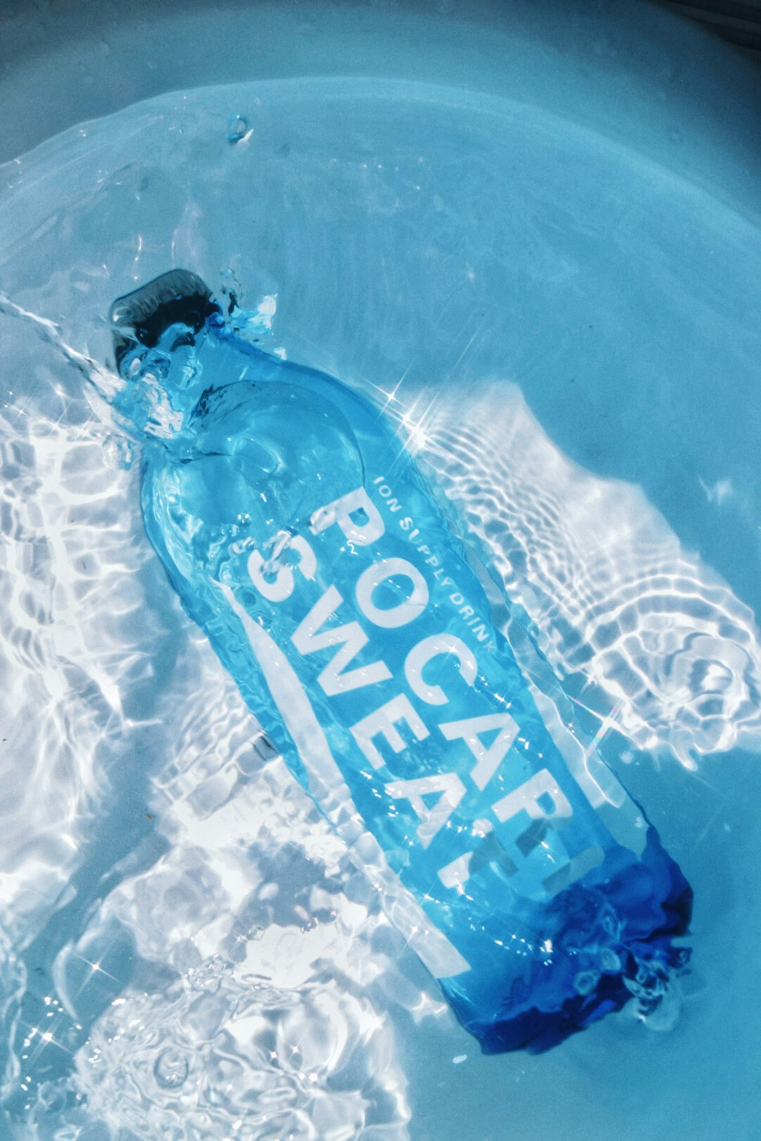 ขวดสีน้ำเงินที่มีป้ายว่า ROCAP SWEAT ลอยอยู่ในน้ำใส