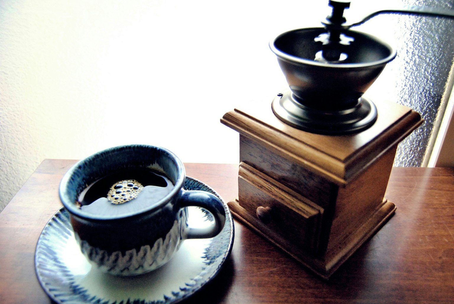 Una scena serena con una tazza di caffè e un macinacaffè in legno