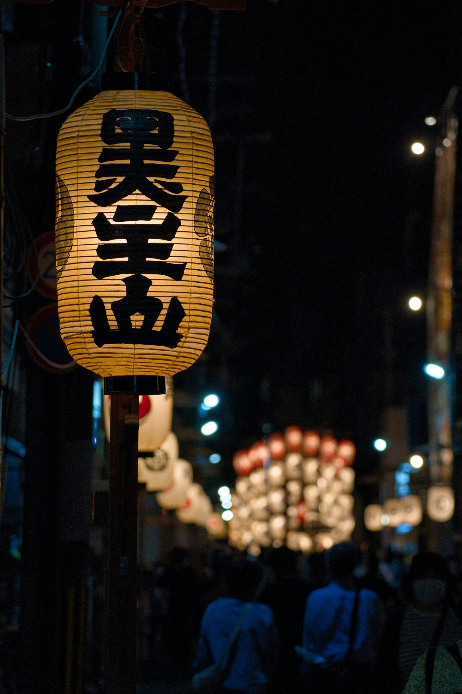 Illuminated lantern and silhouettes of people in a night street