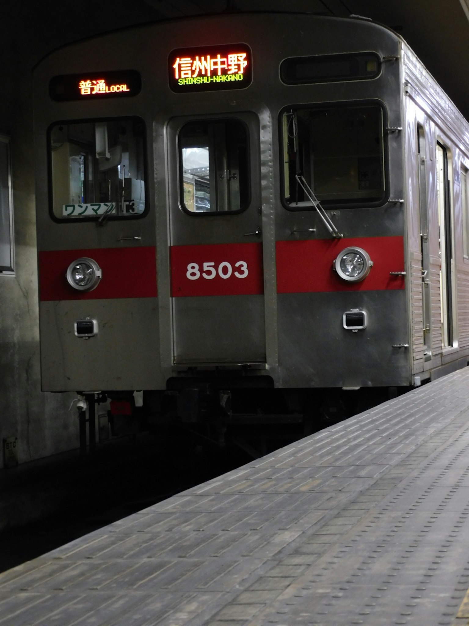รถไฟสีเงินที่มีแถบสีแดงจอดอยู่ที่สถานี