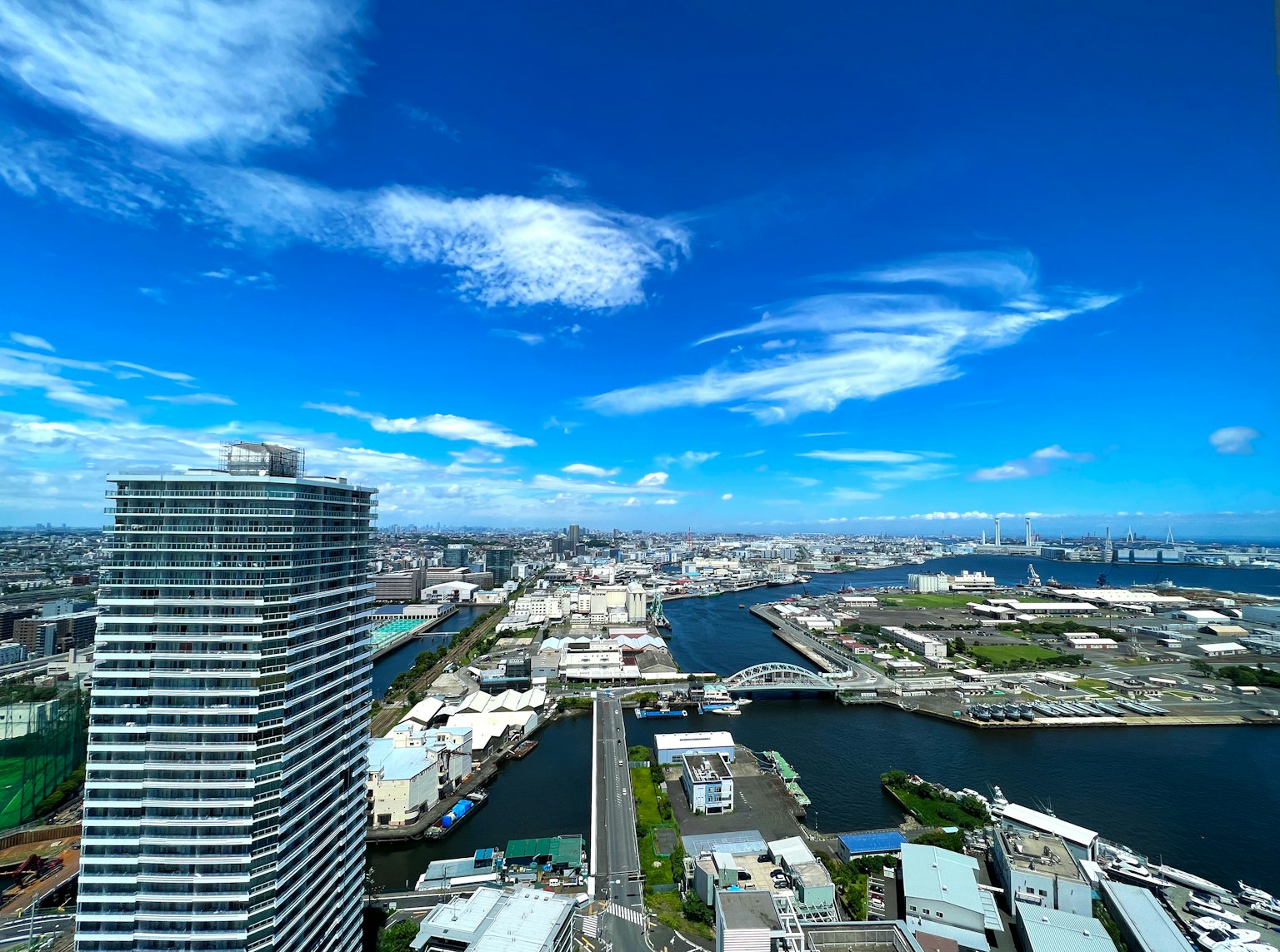 ภาพพาโนรามาจากตึกระฟ้าที่แสดงให้เห็นท้องฟ้าสีฟ้าสดใส ทิวทัศน์เมือง แม่น้ำ และอาคาร