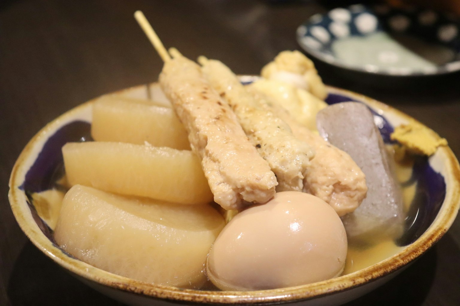 Un tazón de oden con daikon, huevo y pollo en brocheta