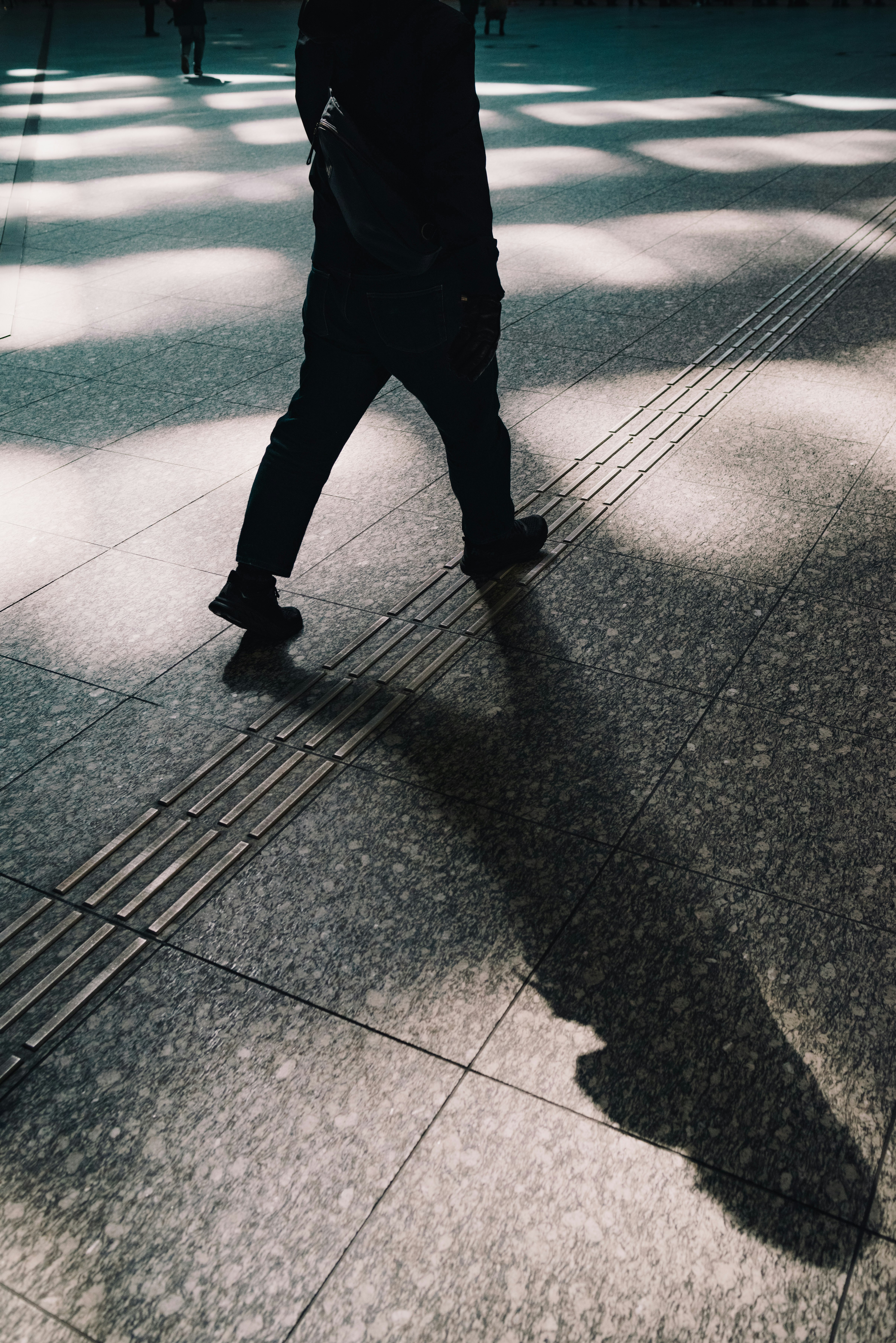 städtischer Gehweg mit Fußgänger mit langen Schatten beim Überqueren