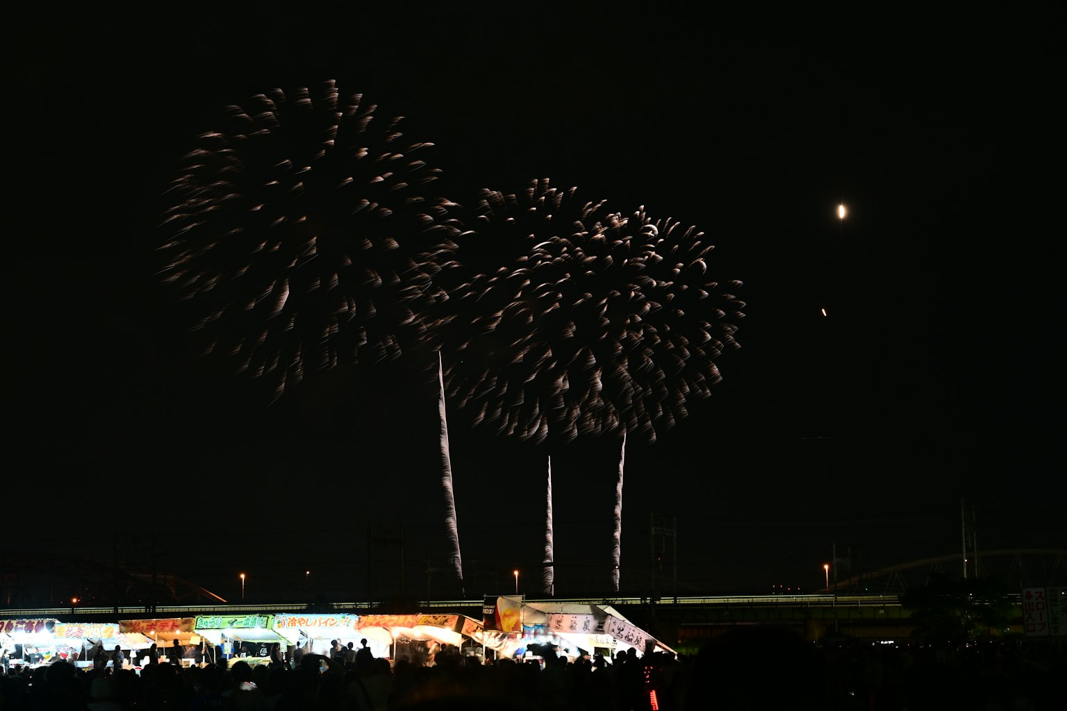 Fireworks bursting in the night sky with silhouettes of spectators