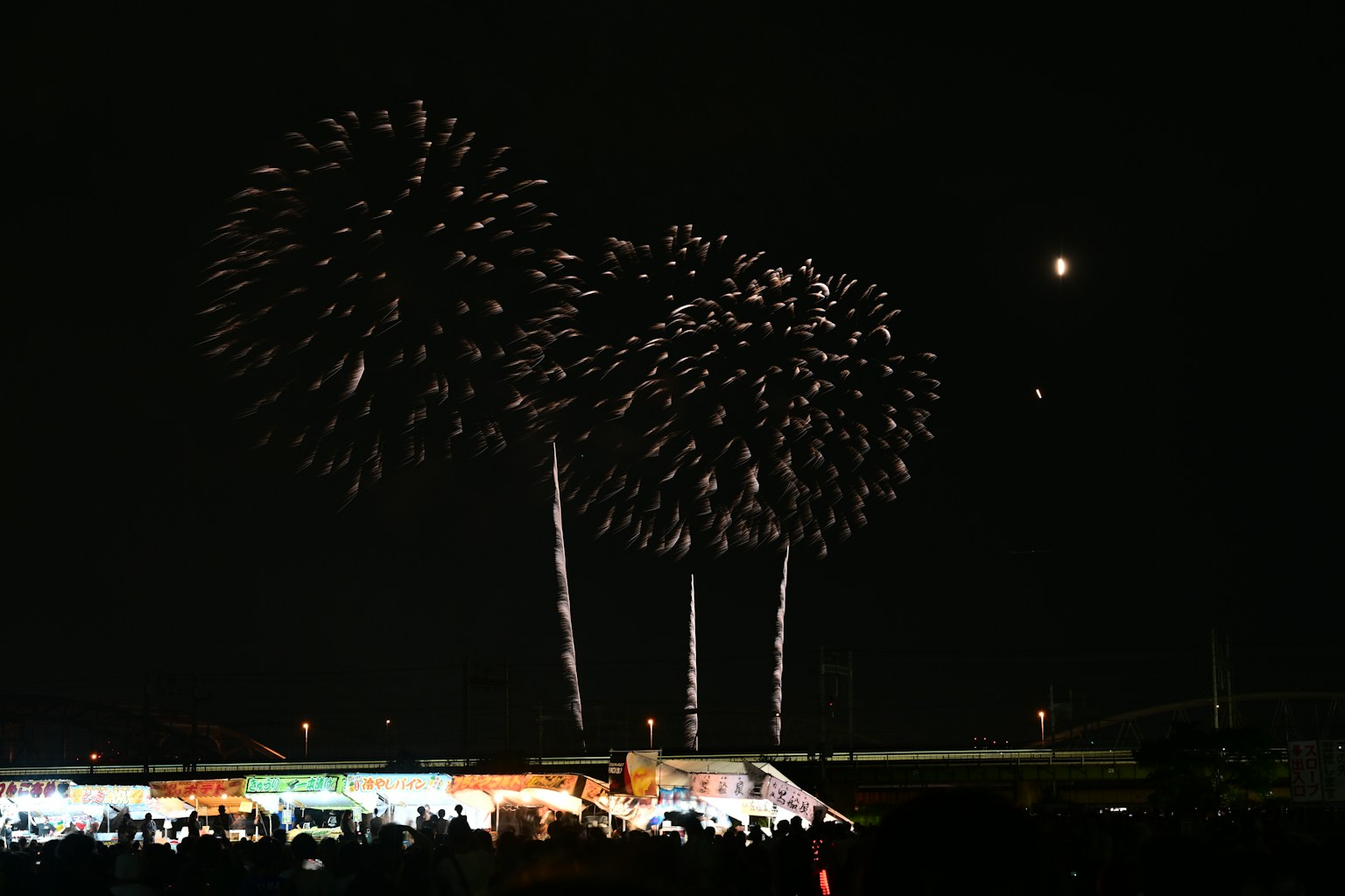Fireworks bursting in the night sky with silhouettes of spectators
