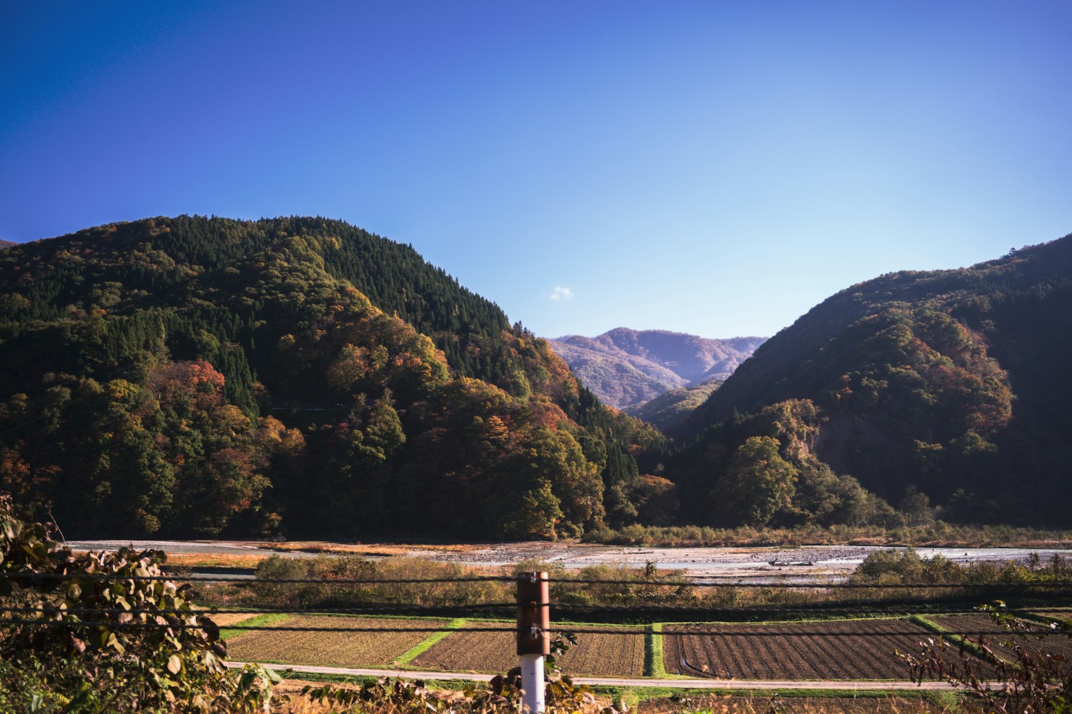 Vista panoramica di montagne e di un fiume calmo sotto un cielo azzurro