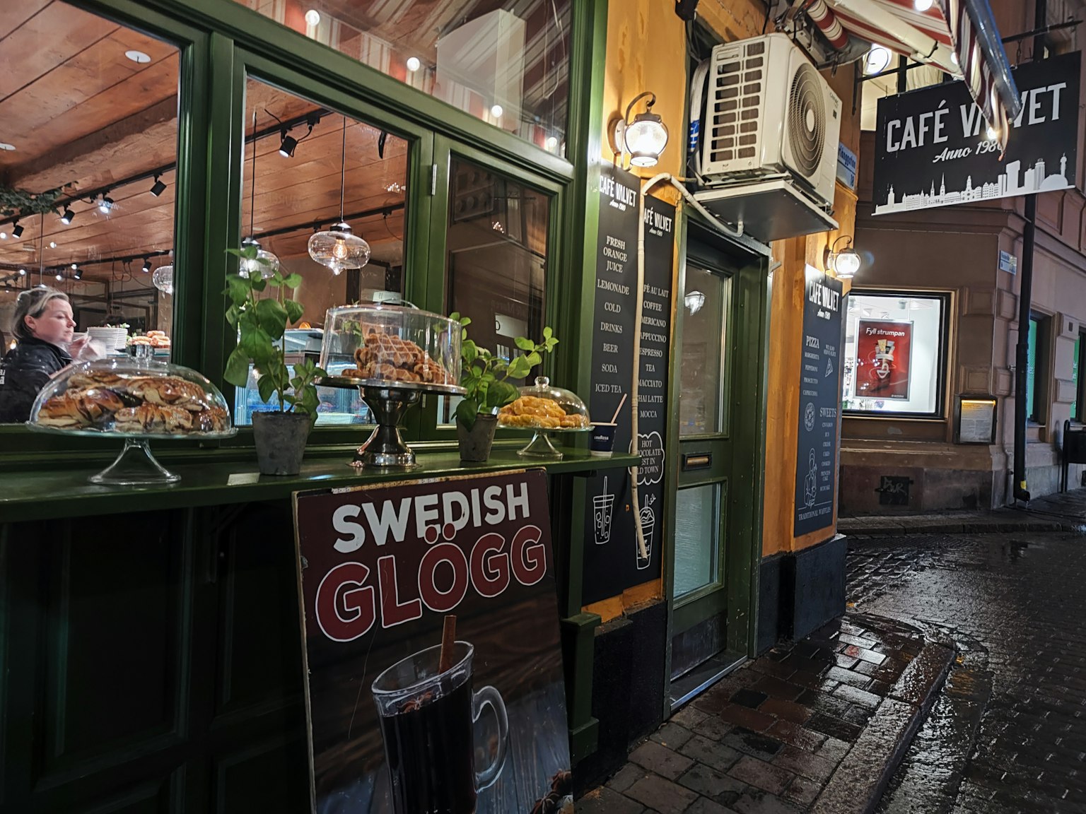 Extérieur d'un café présentant du Glögg suédois avec des fenêtres vertes et une signalétique