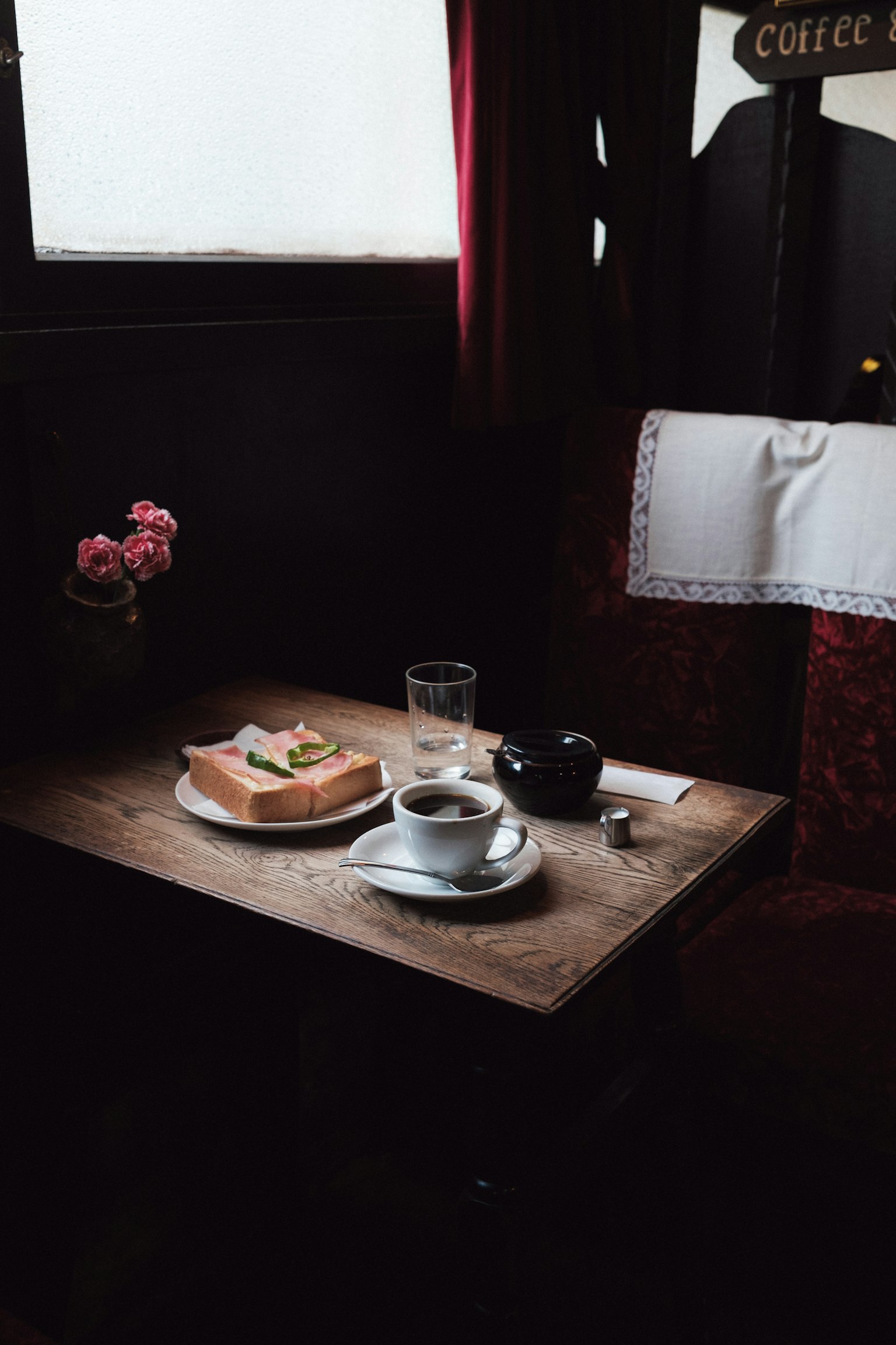 Une table en bois avec des toasts et du café Lumière douce entrant par la fenêtre Rideaux rouges et vase de fleurs présents