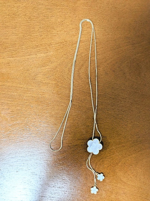 dây đeo móc treo có charm hoa trắng trên nền gỗ