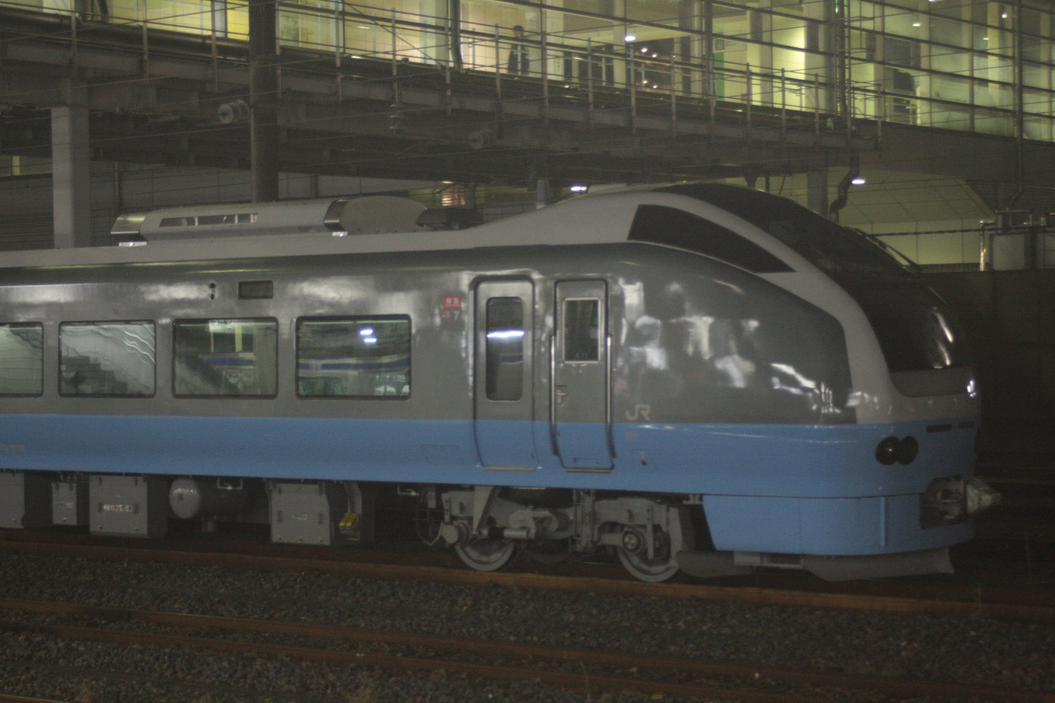 Treno blu parcheggiato su una piattaforma di stazione con architettura moderna sullo sfondo