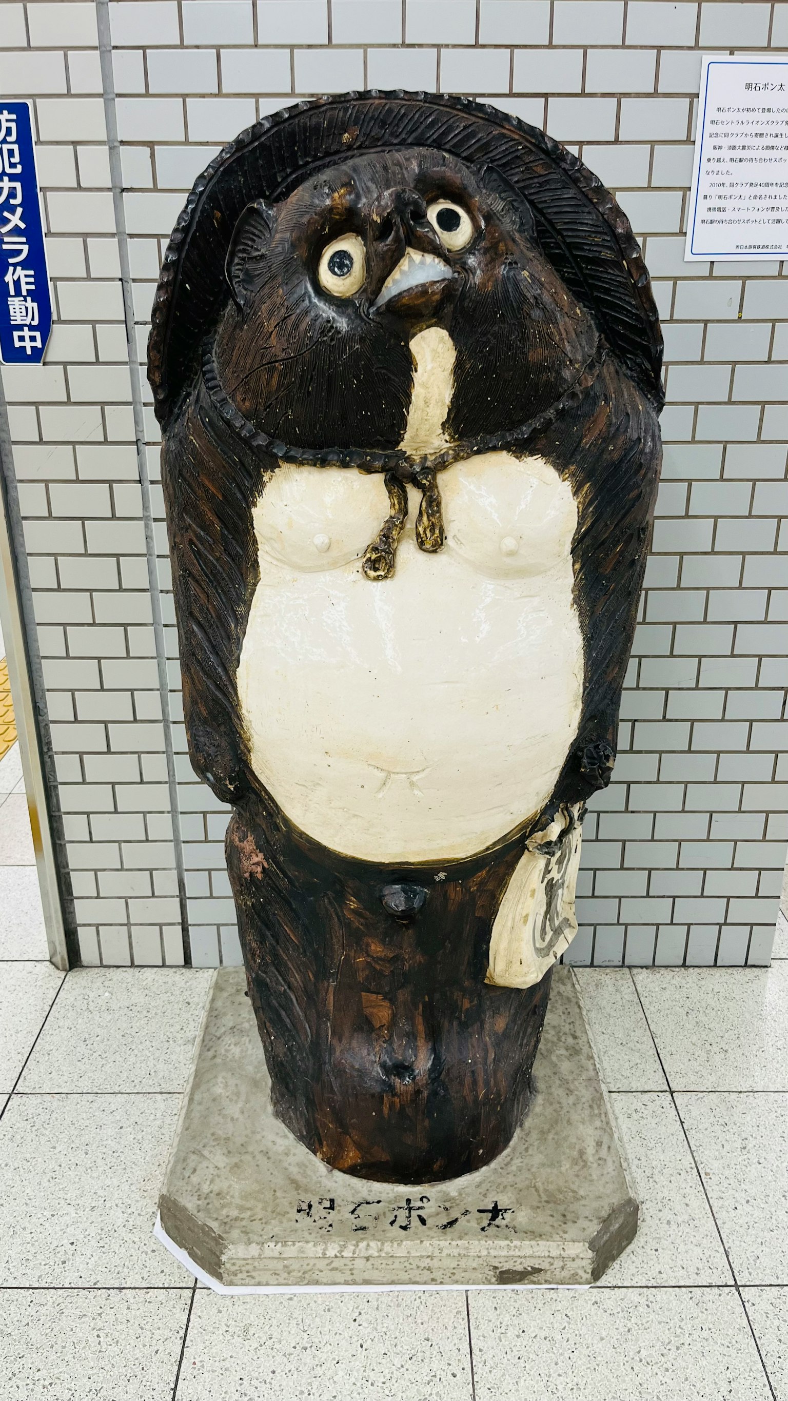 Una statua di tanuki nero che si trova all'interno di una stazione ferroviaria