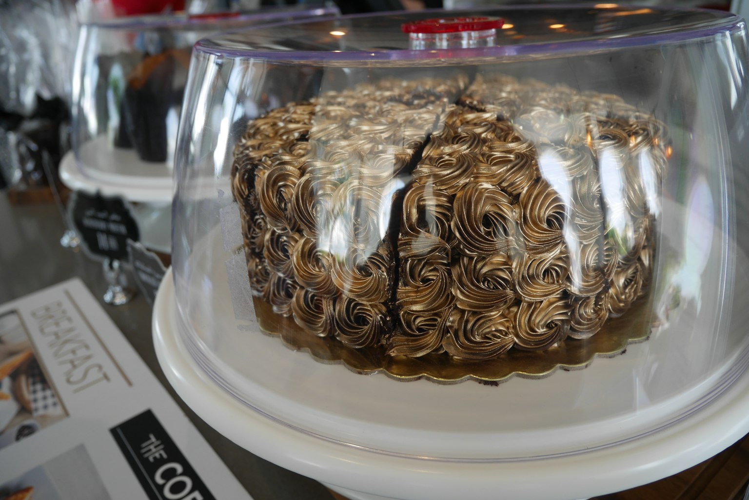 A beautifully designed rose-patterned cake under a glass dome