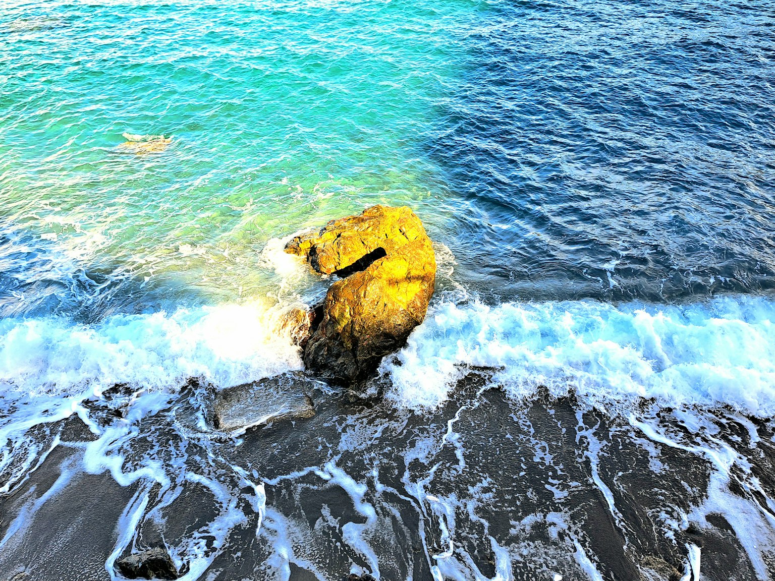 A scenic view of blue ocean waves crashing against a rock