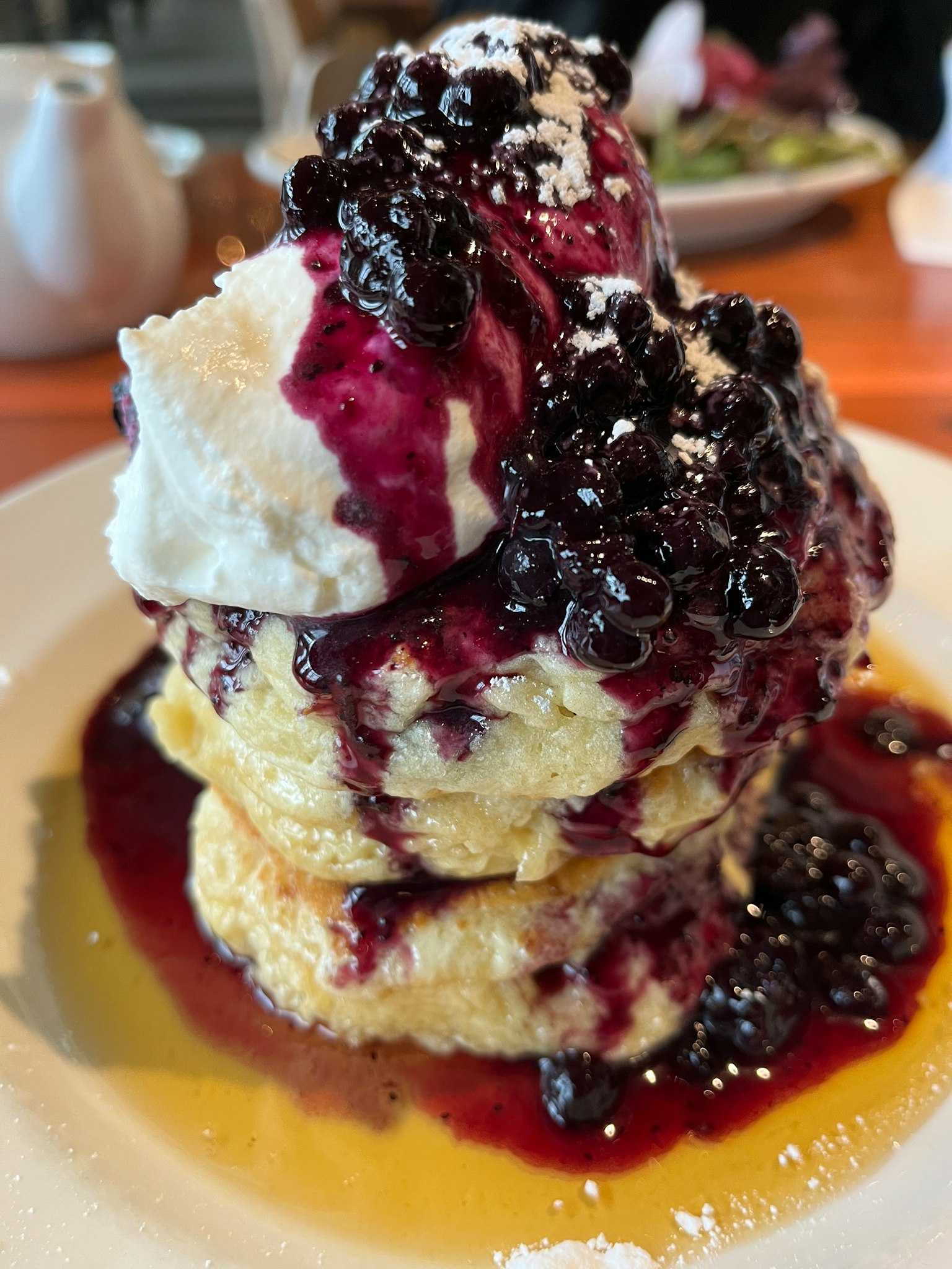 Empilement de pancakes surmontés de sauce aux myrtilles et de crème fouettée