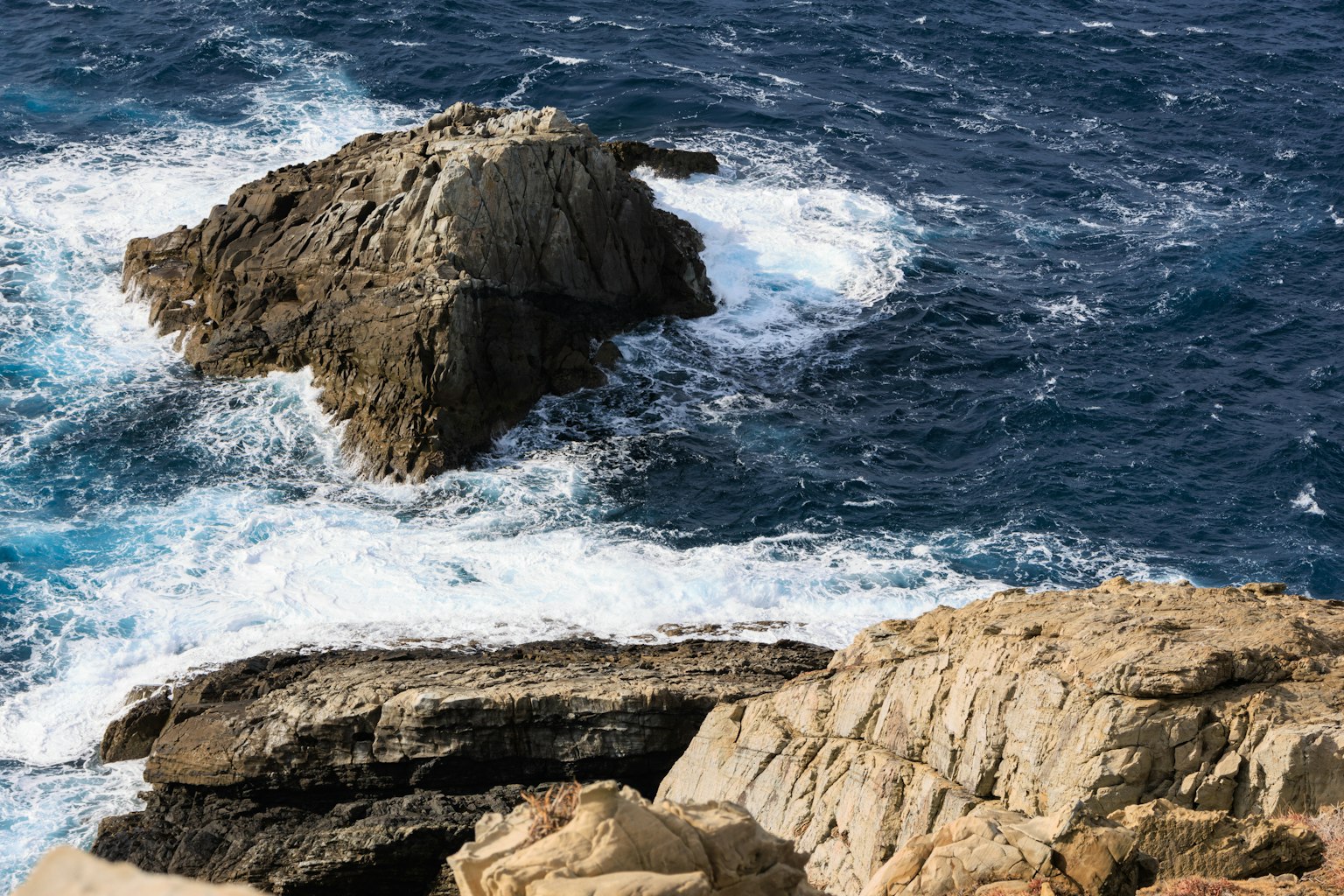 Escena costera con océano azul y formaciones rocosas olas rompiendo contra las rocas