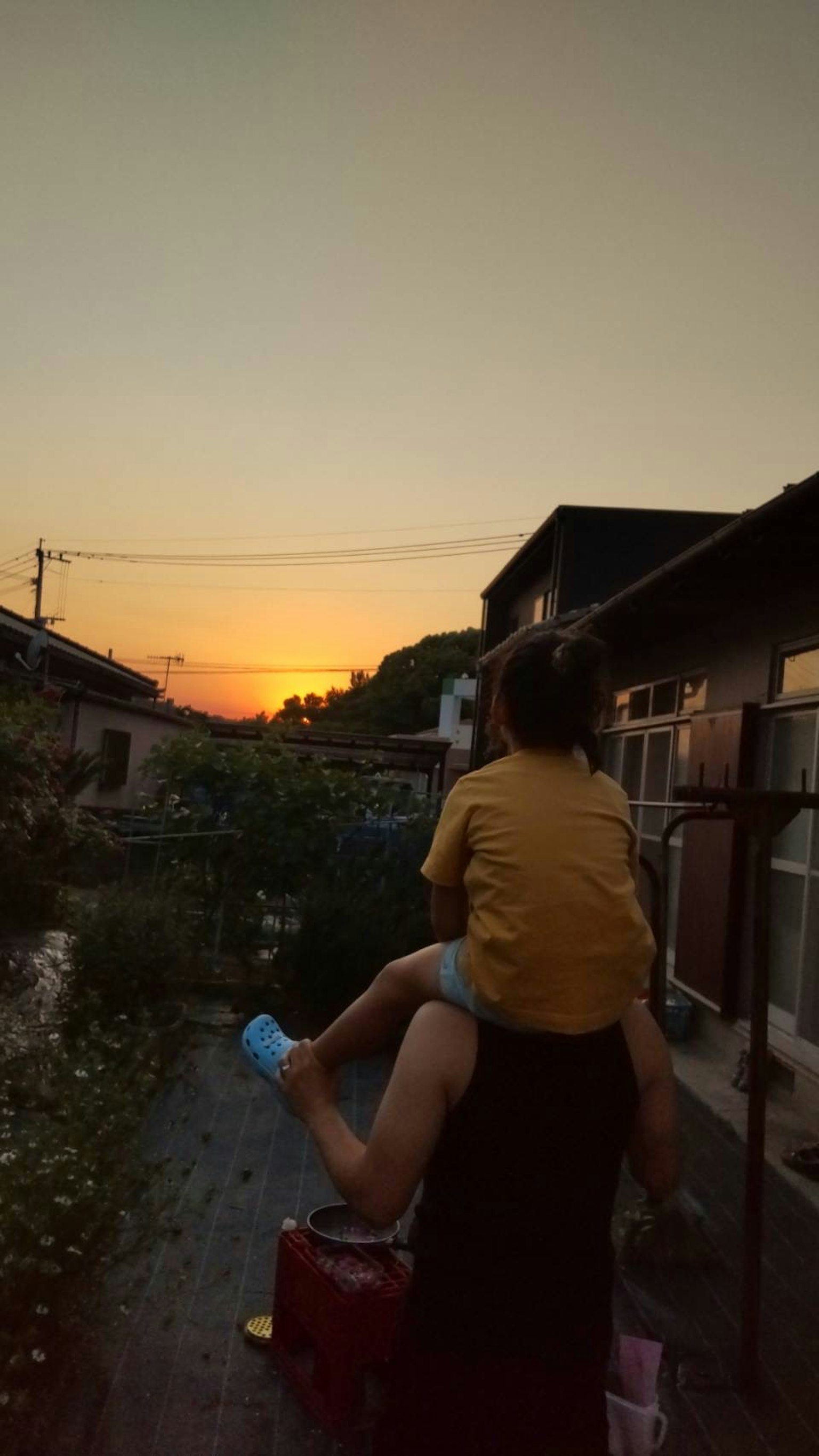 석양을 배경으로 아이를 태운 부모의 실루엣