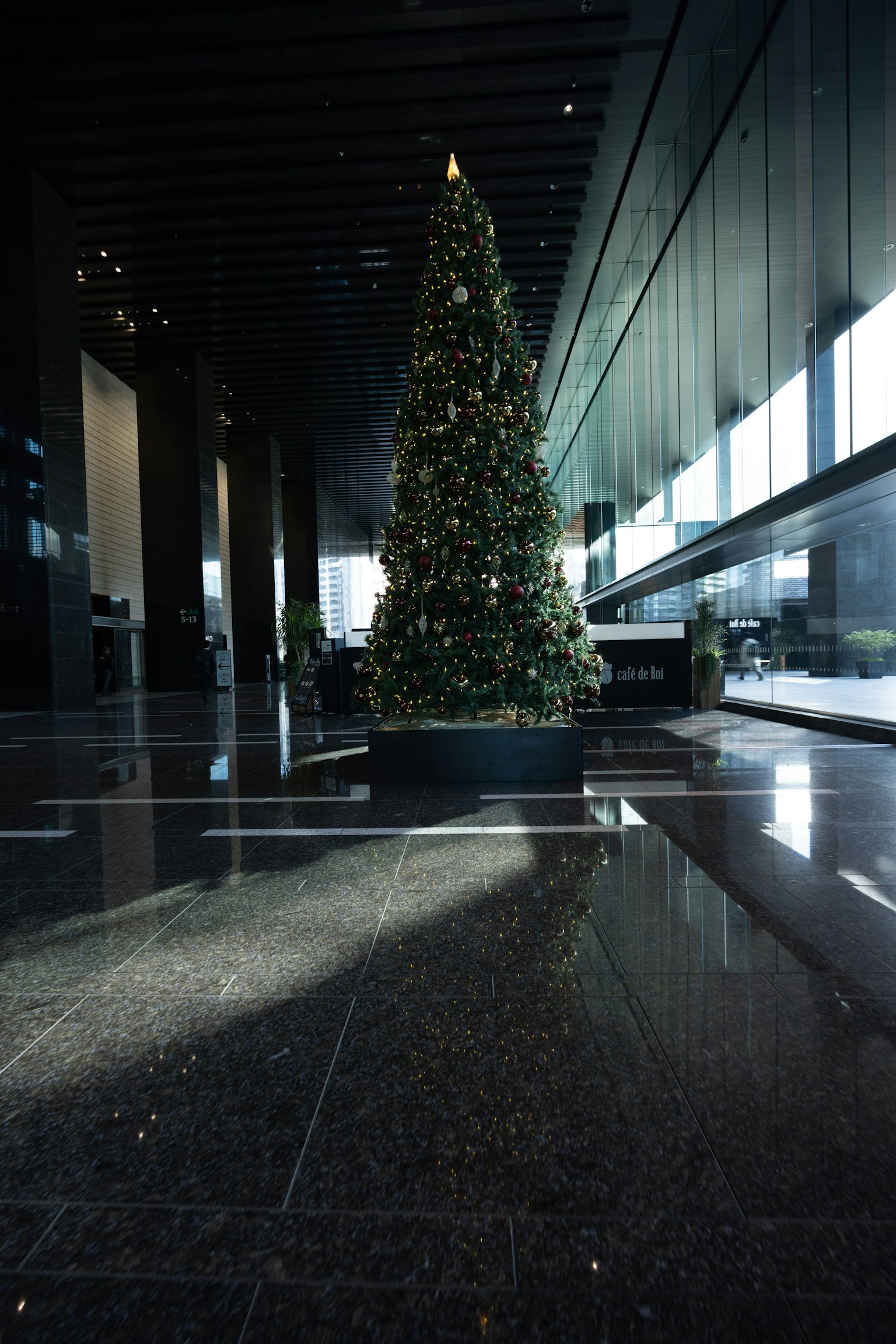 ต้นคริสต์มาสที่ตกแต่งด้วยไฟในล็อบบี้สมัยใหม่ที่มีพื้นเงา