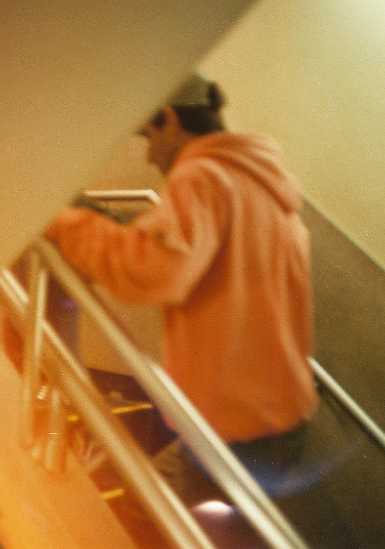 Une personne en tenue de travail orange montant des escaliers de dos