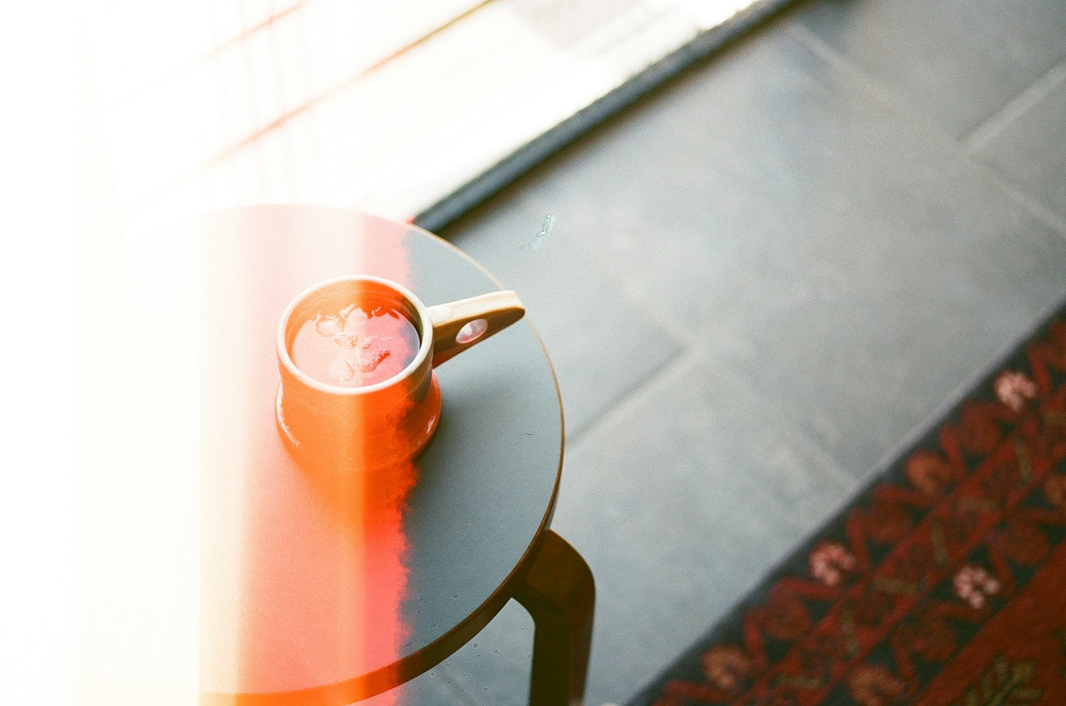 Una taza de café en una mesa con una alfombra decorativa visible en una habitación acogedora