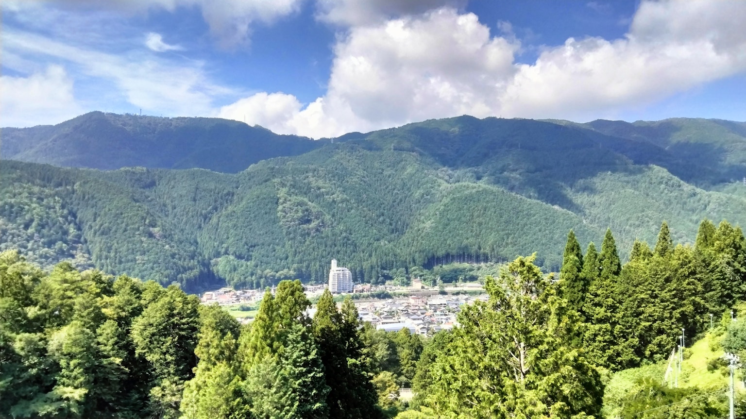 Una vista panoramica di montagne verdi sotto un cielo blu con una città nella valle