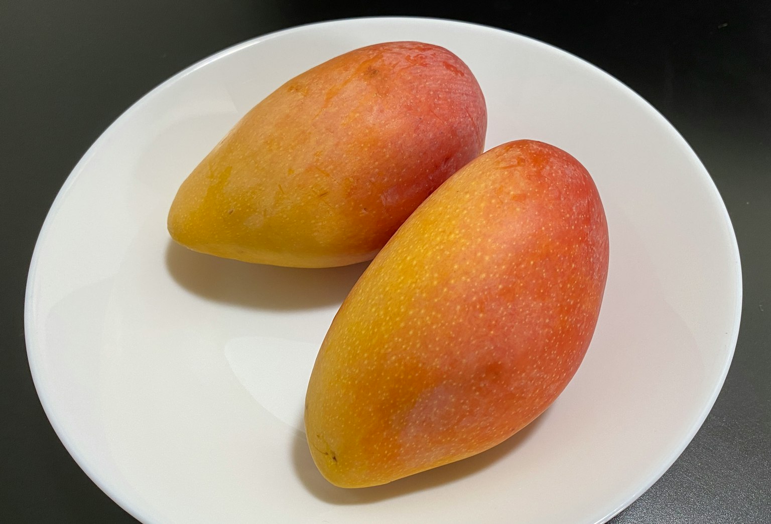 Due mango maturi su un piatto bianco