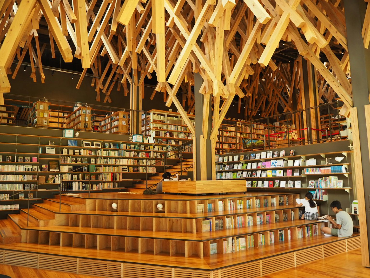 Innenansicht einer einzigartig gestalteten Bibliothek mit Holzstrukturen Regale voller Bücher und sitzenden Personen