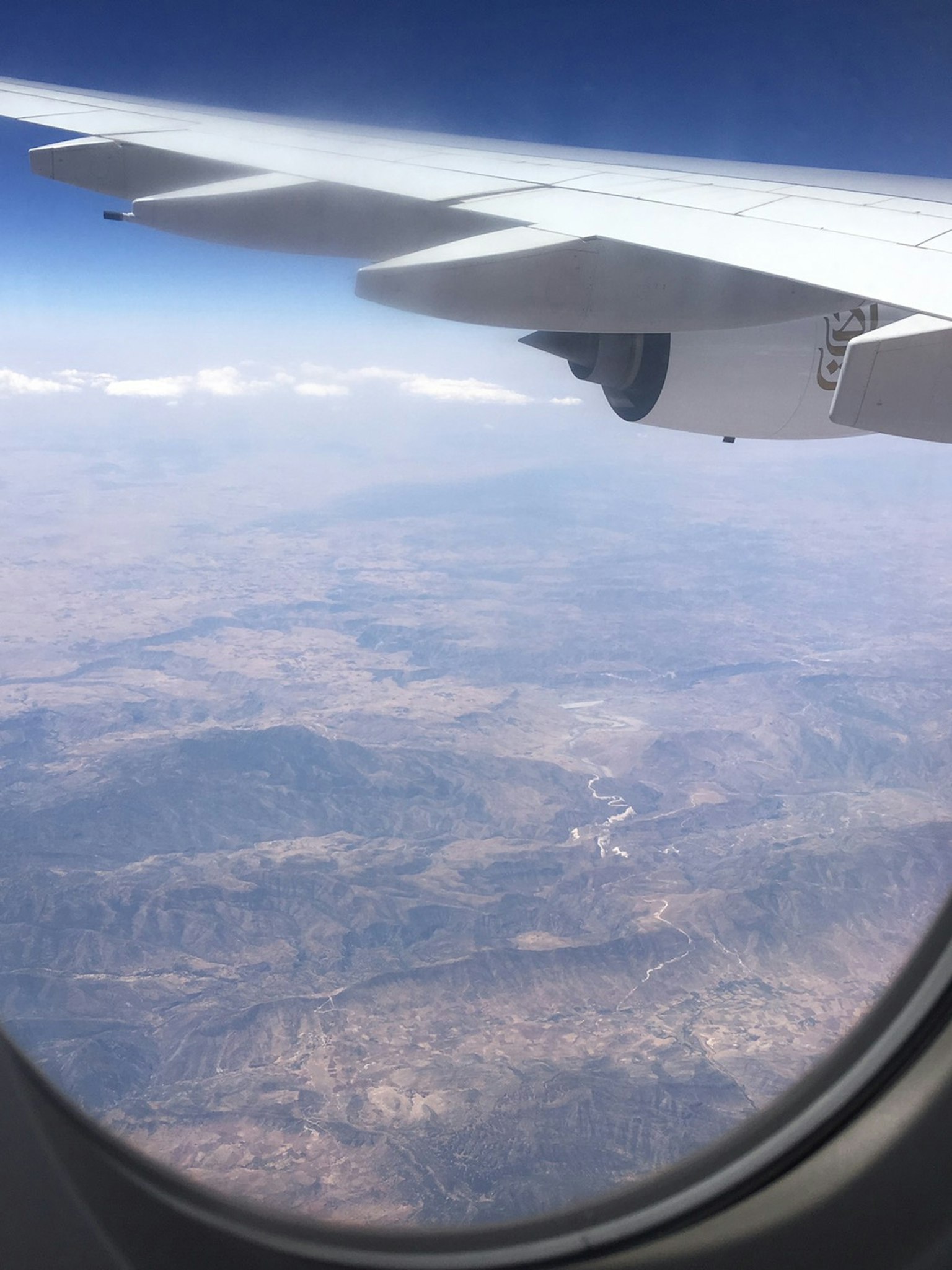 Vista de montañas y terreno vasto desde una ventana de avión