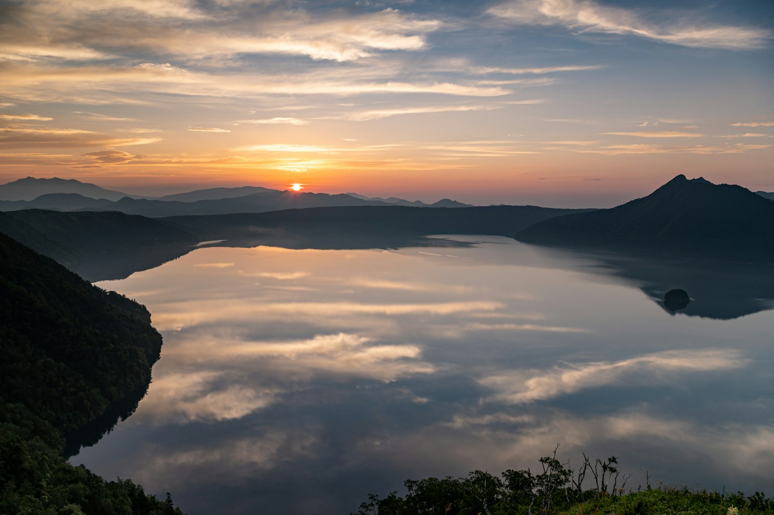 Atardecer escénico sobre un lago tranquilo rodeado de montañas