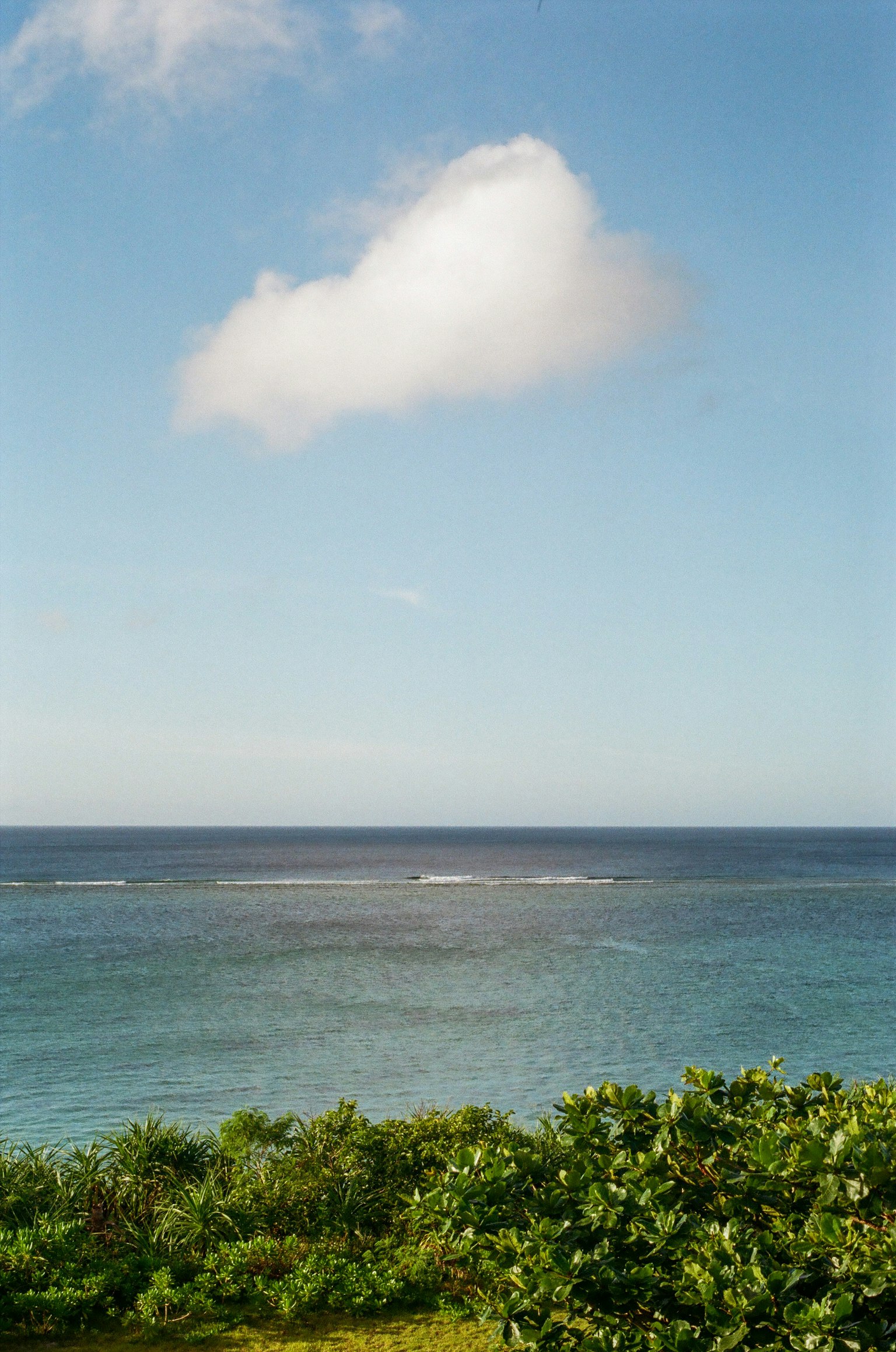 A scenic view of blue ocean and sky with a white cloud