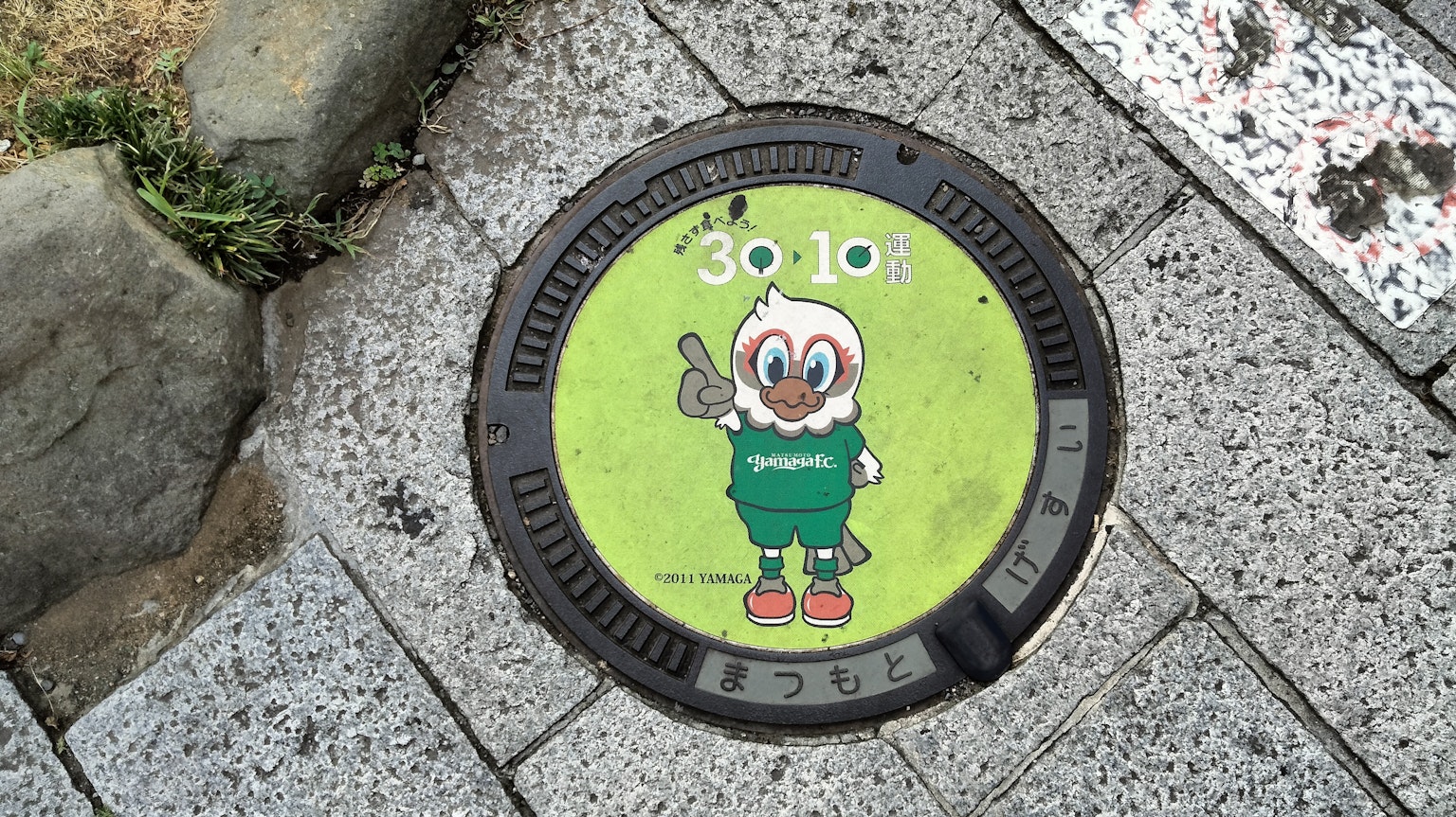 Grüne Kanaldeckel mit einem Cartoon-Charakter