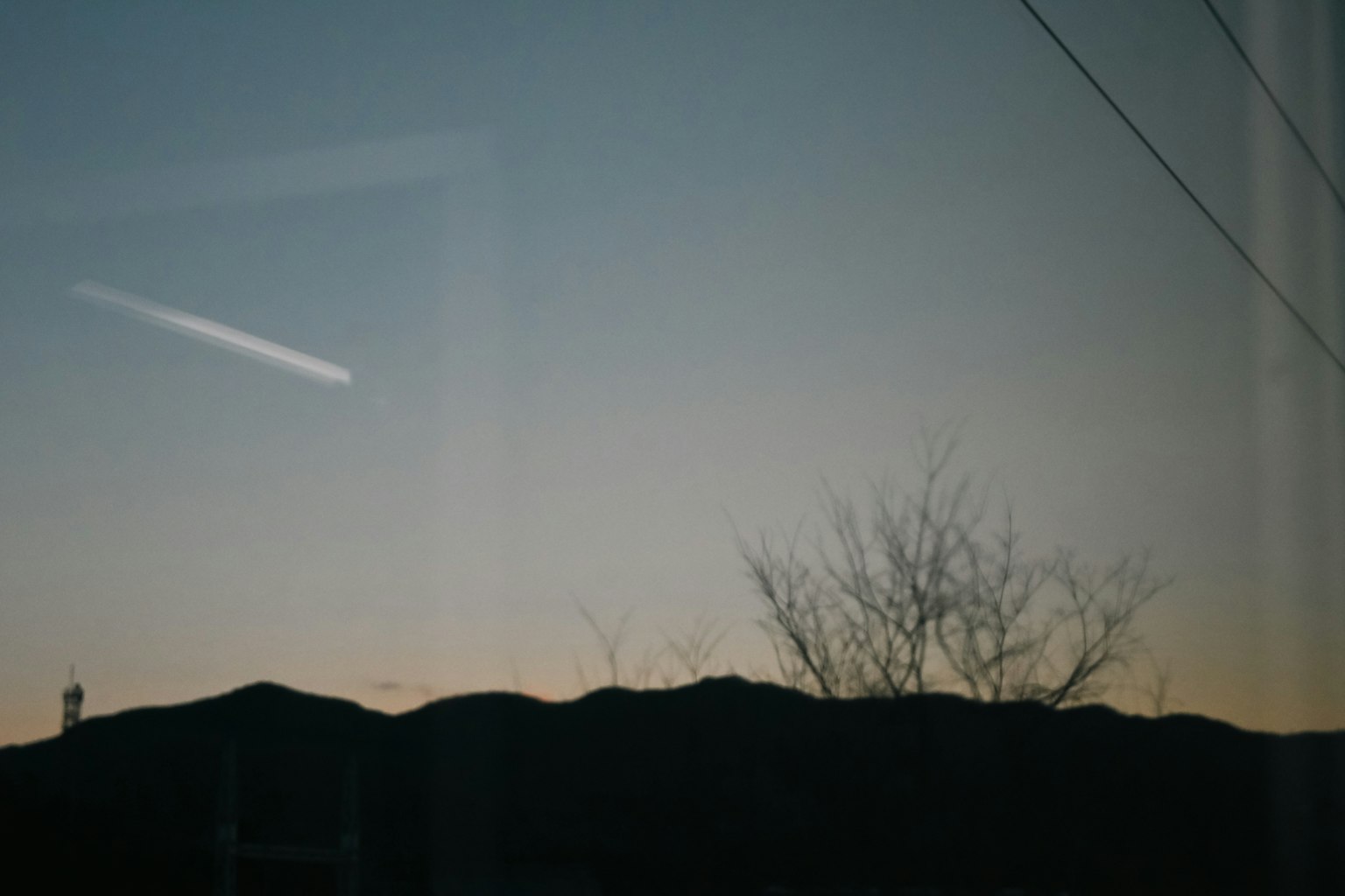 Silueta de montañas con un cielo crepuscular reflejado en una ventana