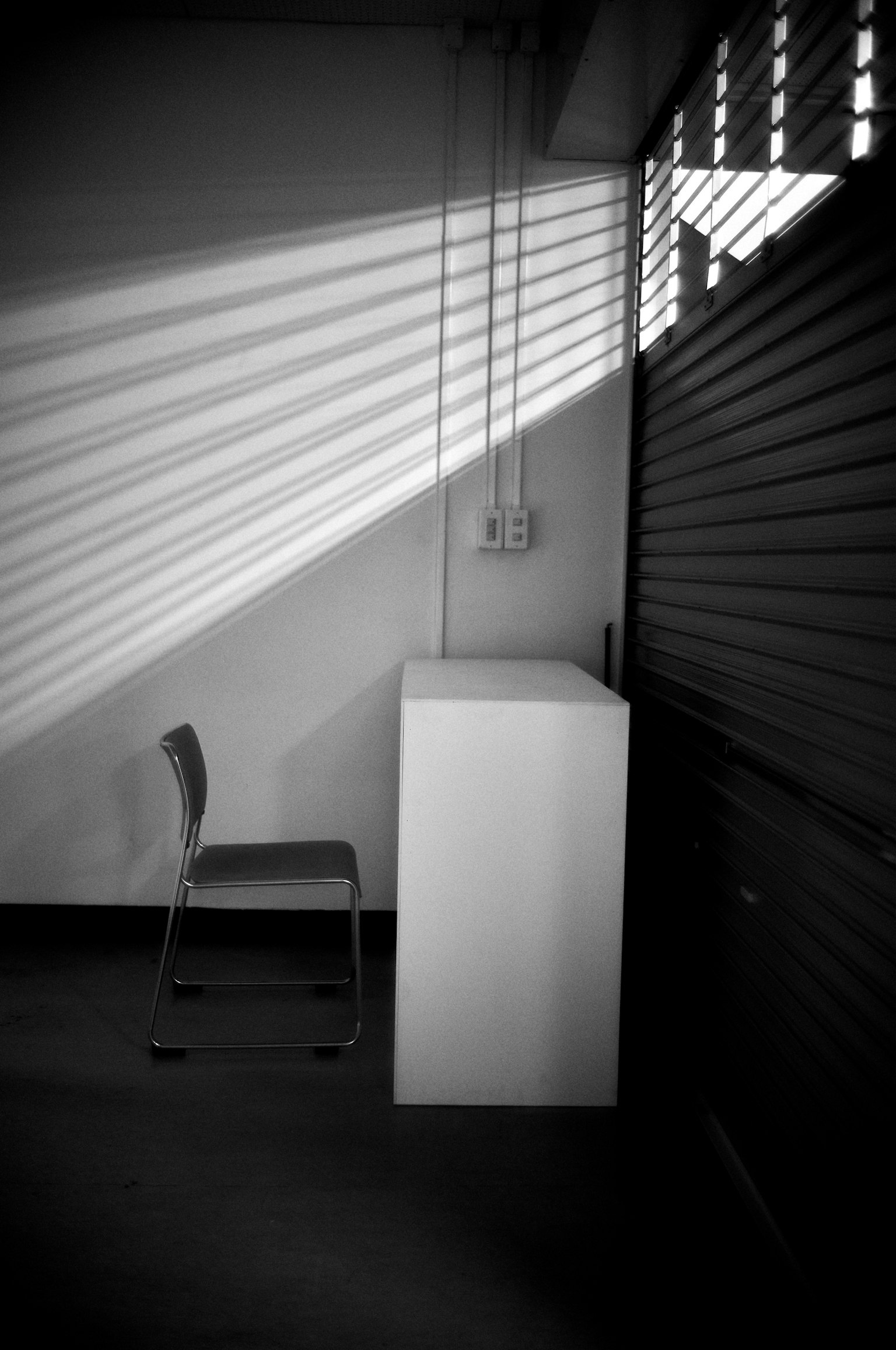 白いテーブルと椅子がある部屋の隅に、光のストライプが落ちている