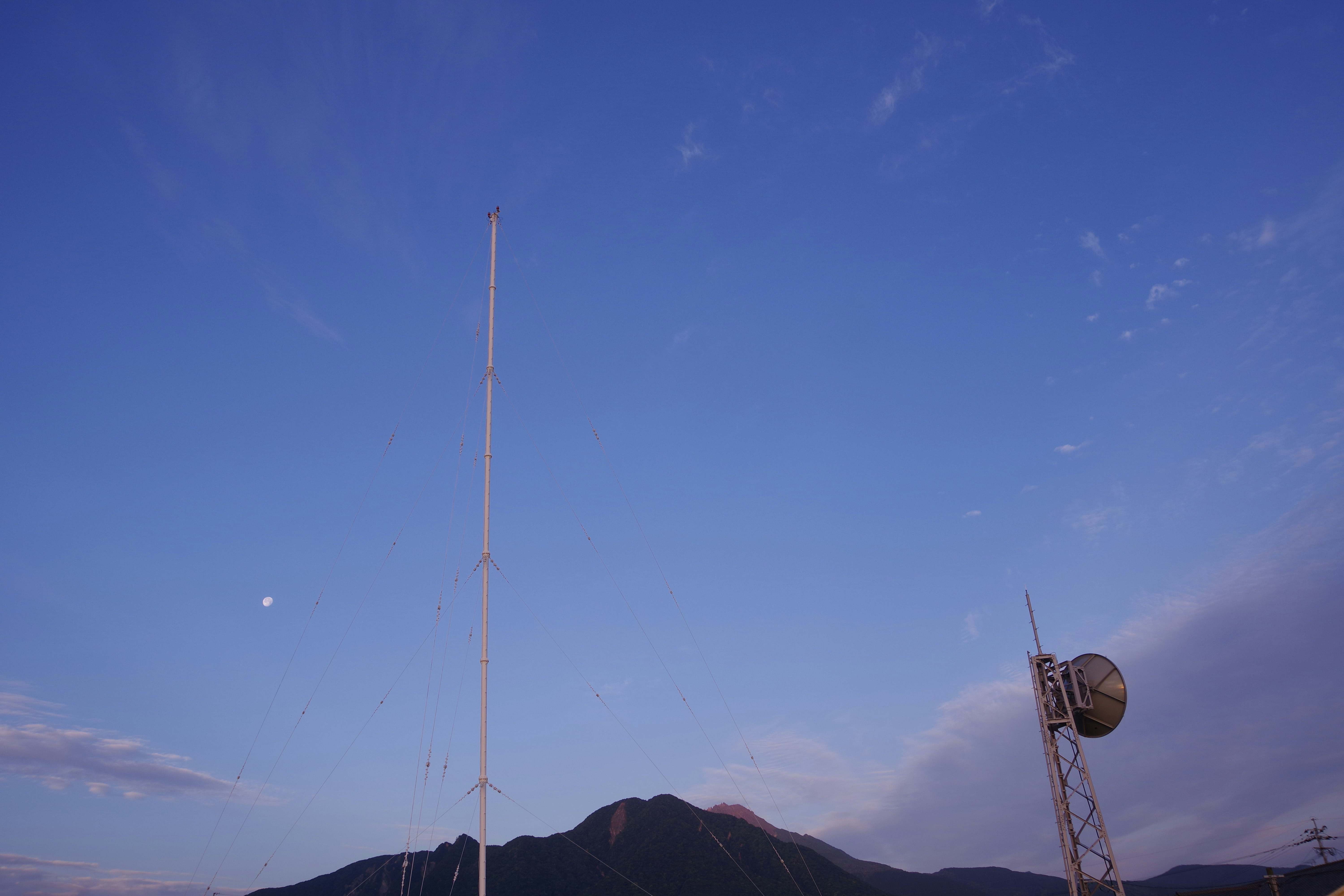 高通信塔和球形天线在蓝天和山脉背景下