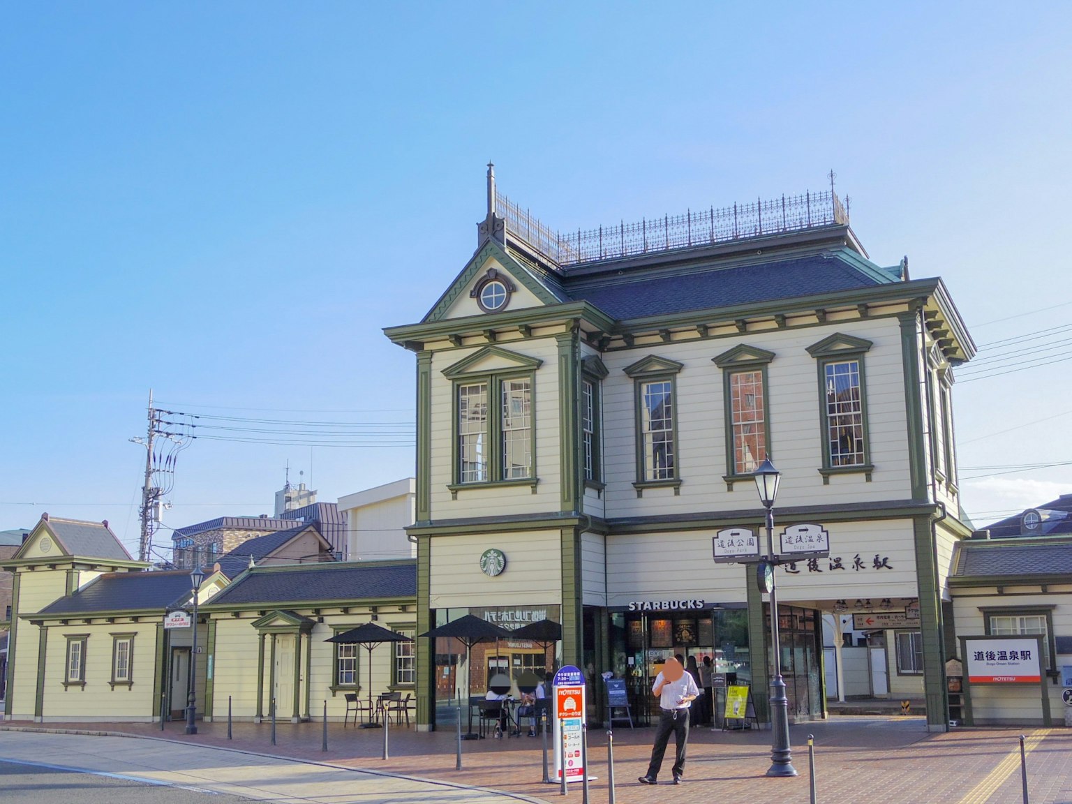 Gare historique avec une façade verte et un paysage environnant