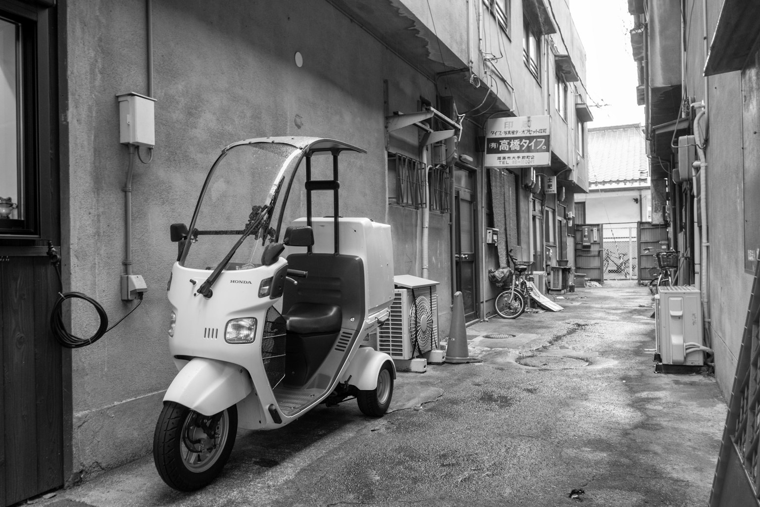 狹窄的小巷中停著一輛白色三輪車和舊建築
