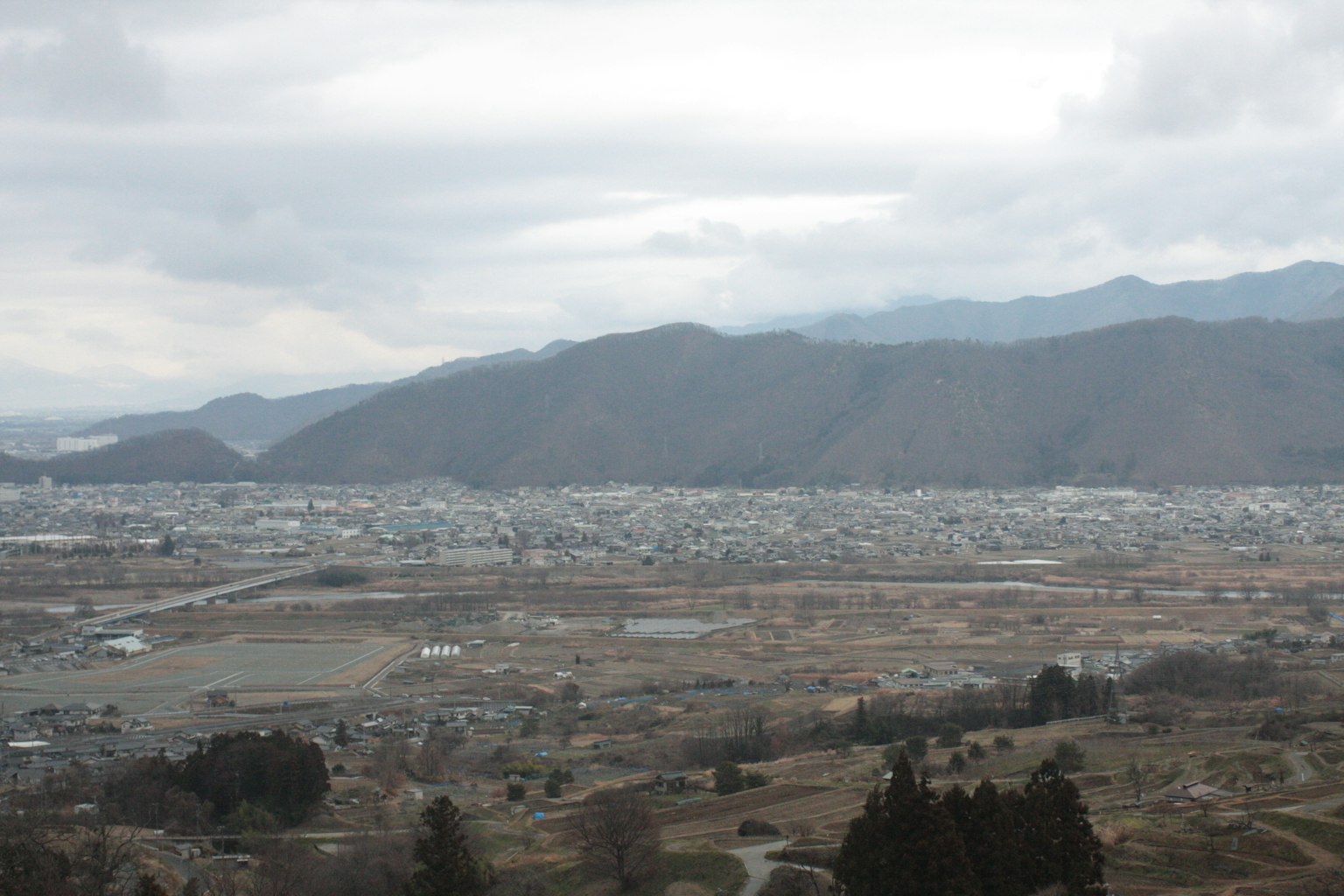 被山脉环绕的城市景观 阴云密布的天空和广阔的平原