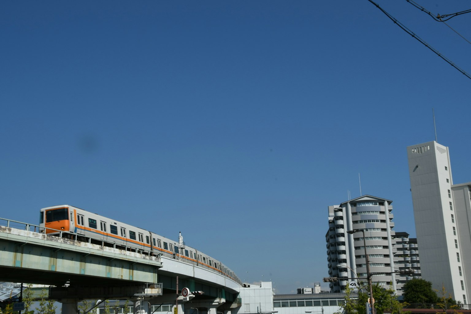Tren circulando bajo un cielo azul claro con edificios modernos