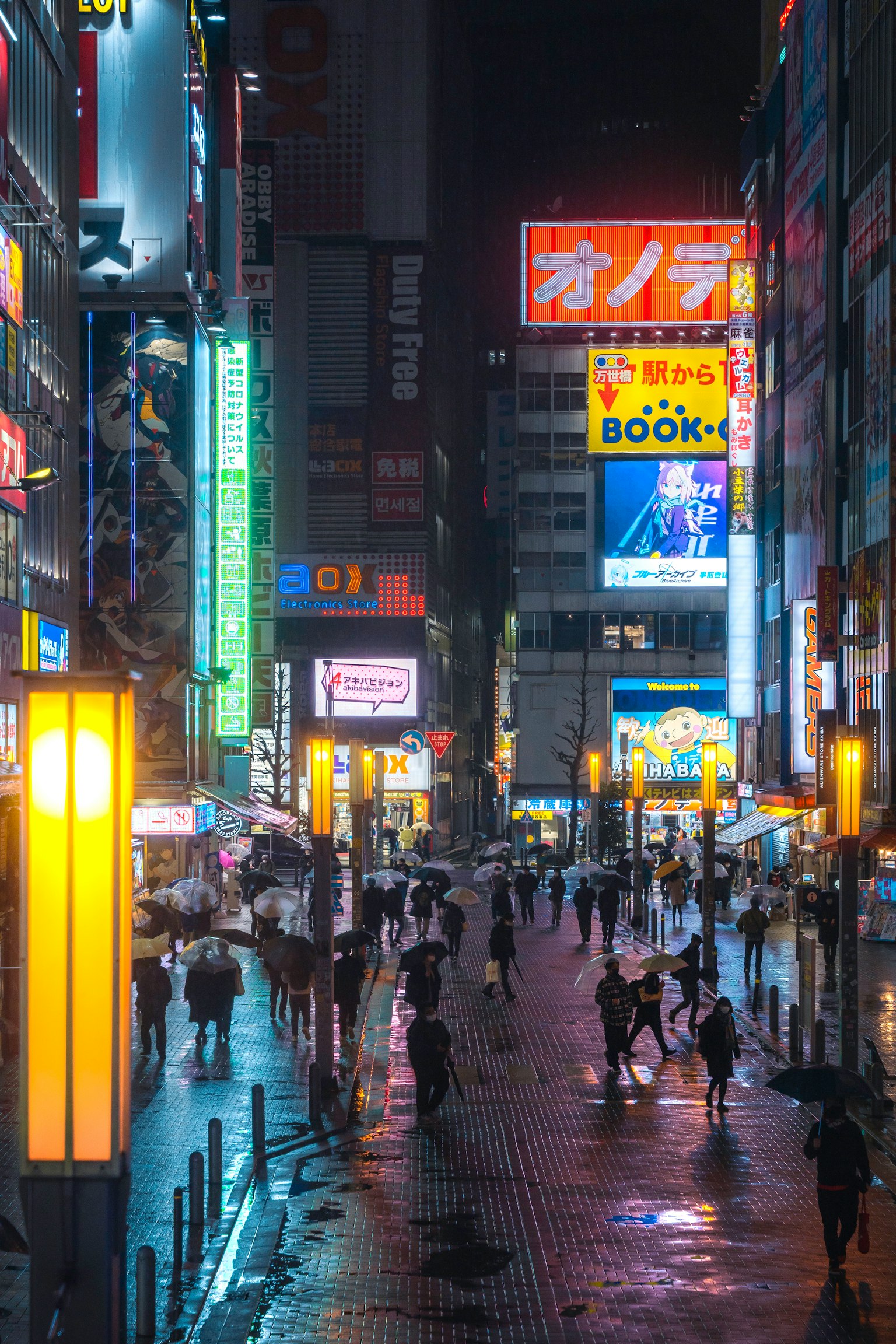 Scena notturna di una strada affollata con insegne al neon e marciapiede bagnato