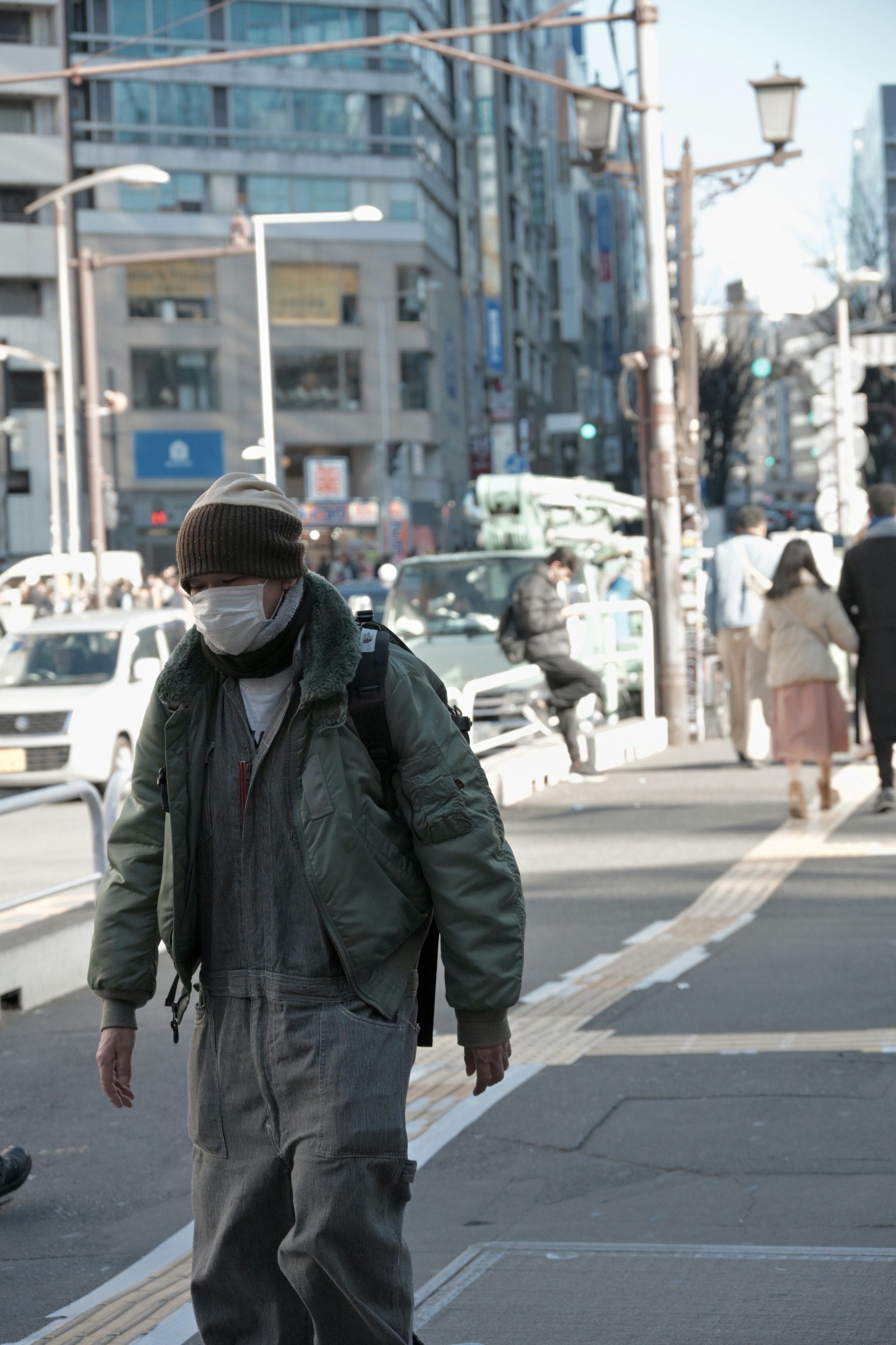 街を歩くマスクをした男性と通行人の風景