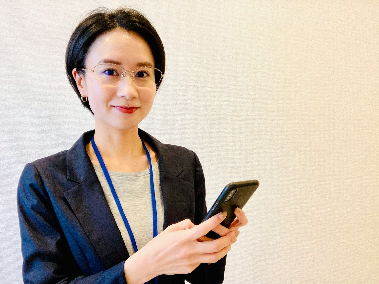Une femme en costume d'affaires souriante tenant un smartphone