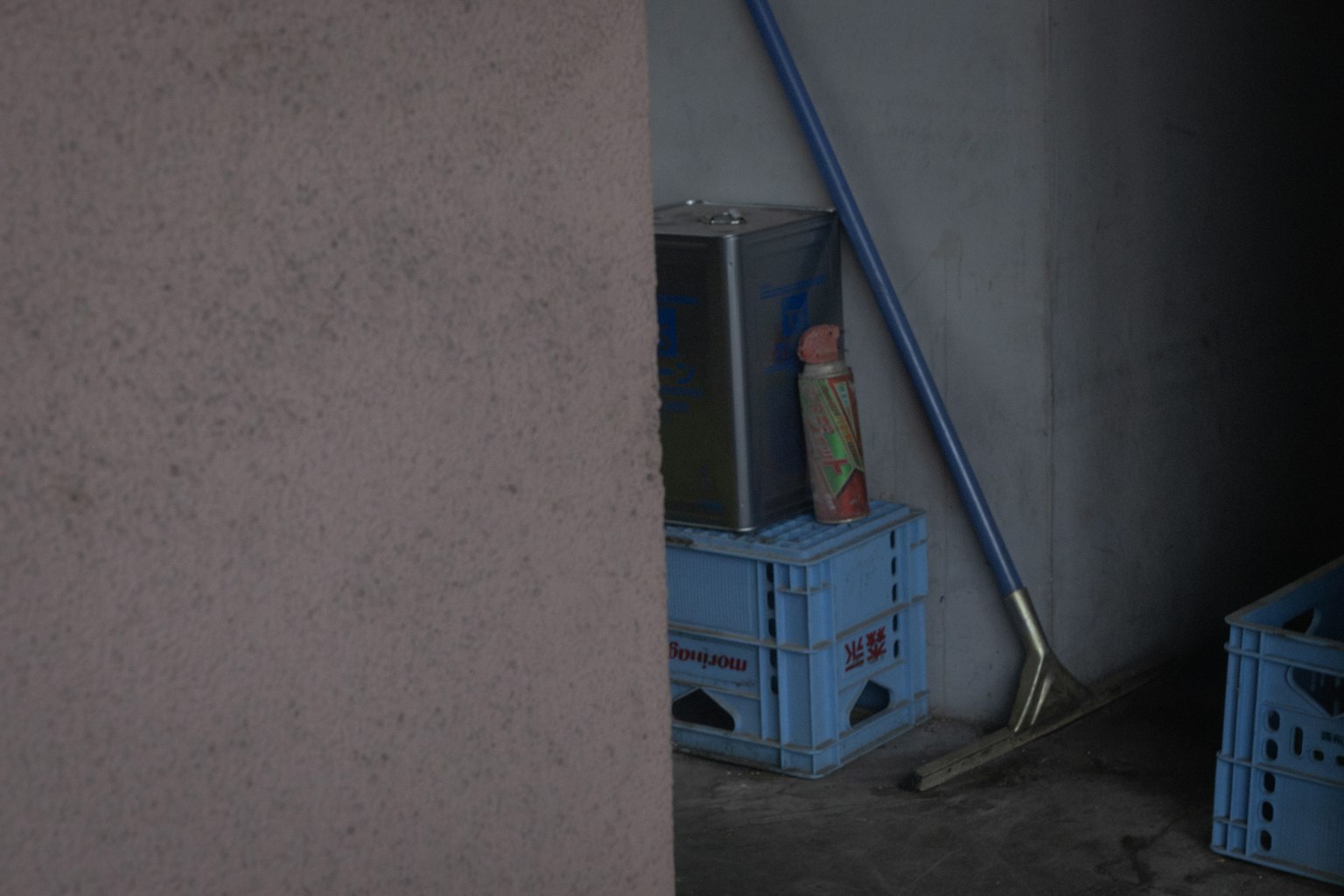 Un espace sombre avec une poupée sur une caisse bleue et des outils de nettoyage
