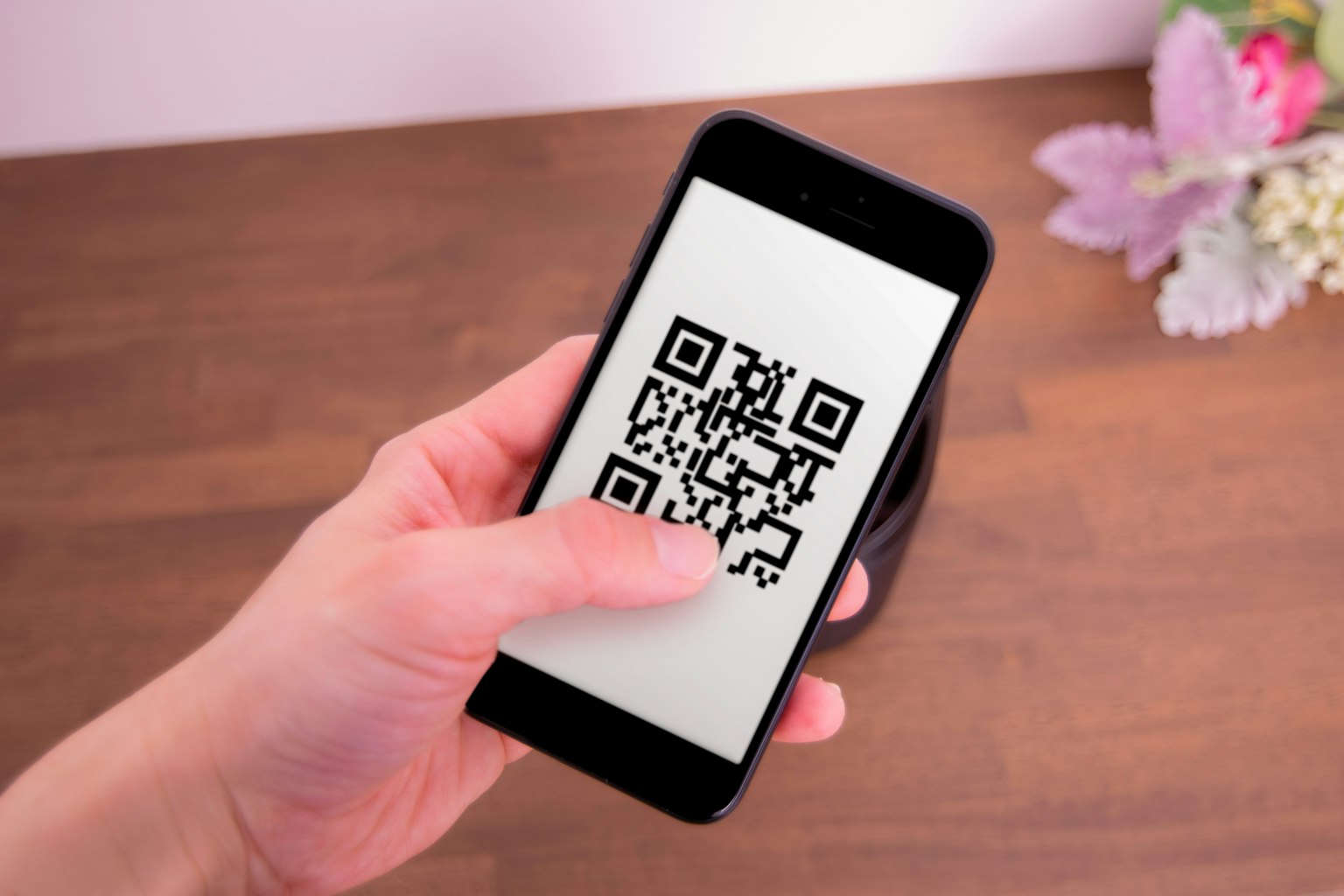 Uno smartphone che mostra un codice QR tenuto in una mano