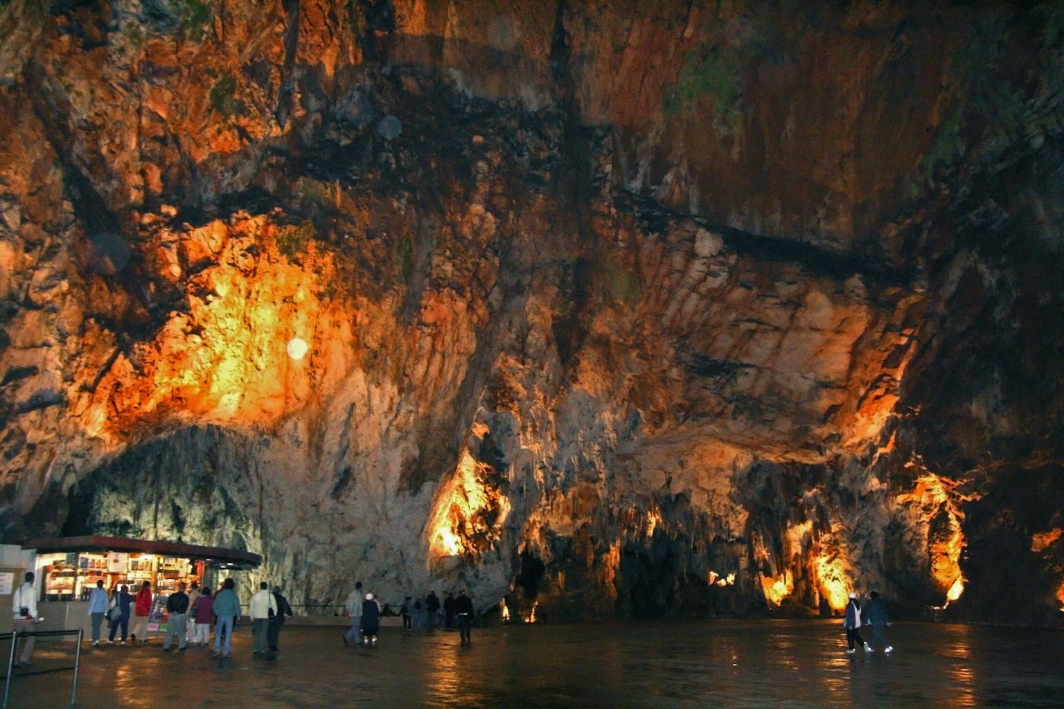 Interior of a cave with people and orange light reflecting on the rocks