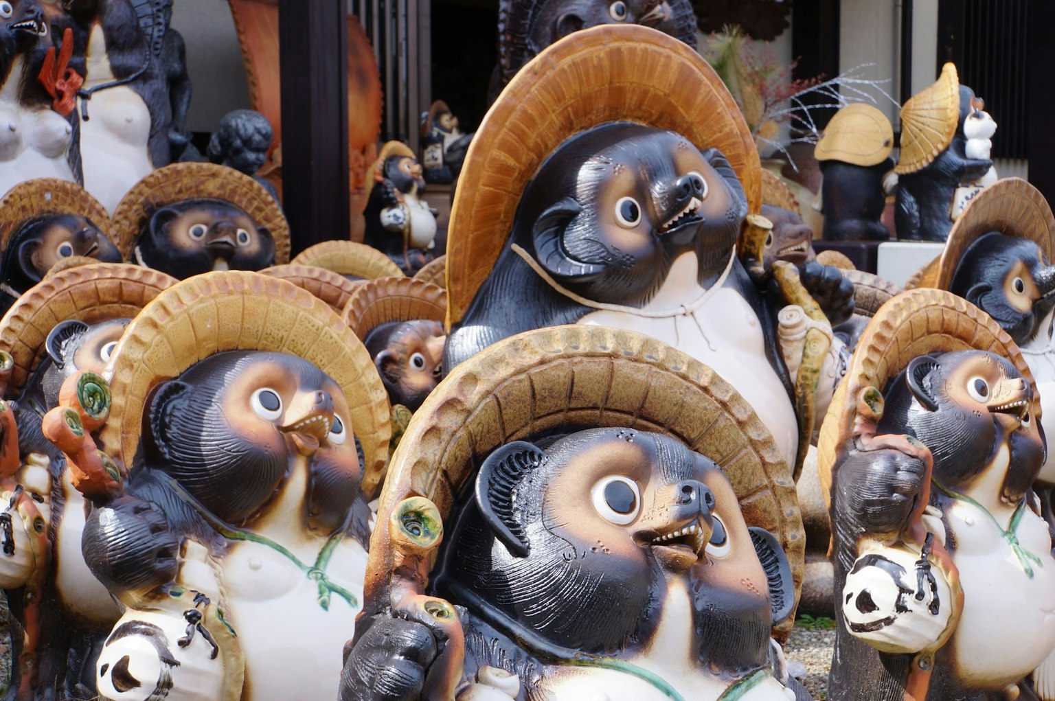 Eine Sammlung von Tanuki-Figuren mit großen Strohhüten